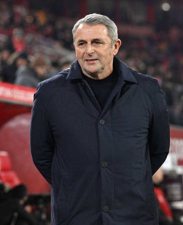 Klaus Allofs hat seine Hände hinter dem Rücken und trägt eine dunkelblaue Jacke.