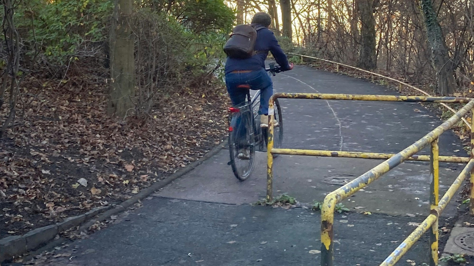 Ein gelbes Drängelgitter auf der Severinsbrücke. Ein Fahrradfahrer fährt links daran vorbei.