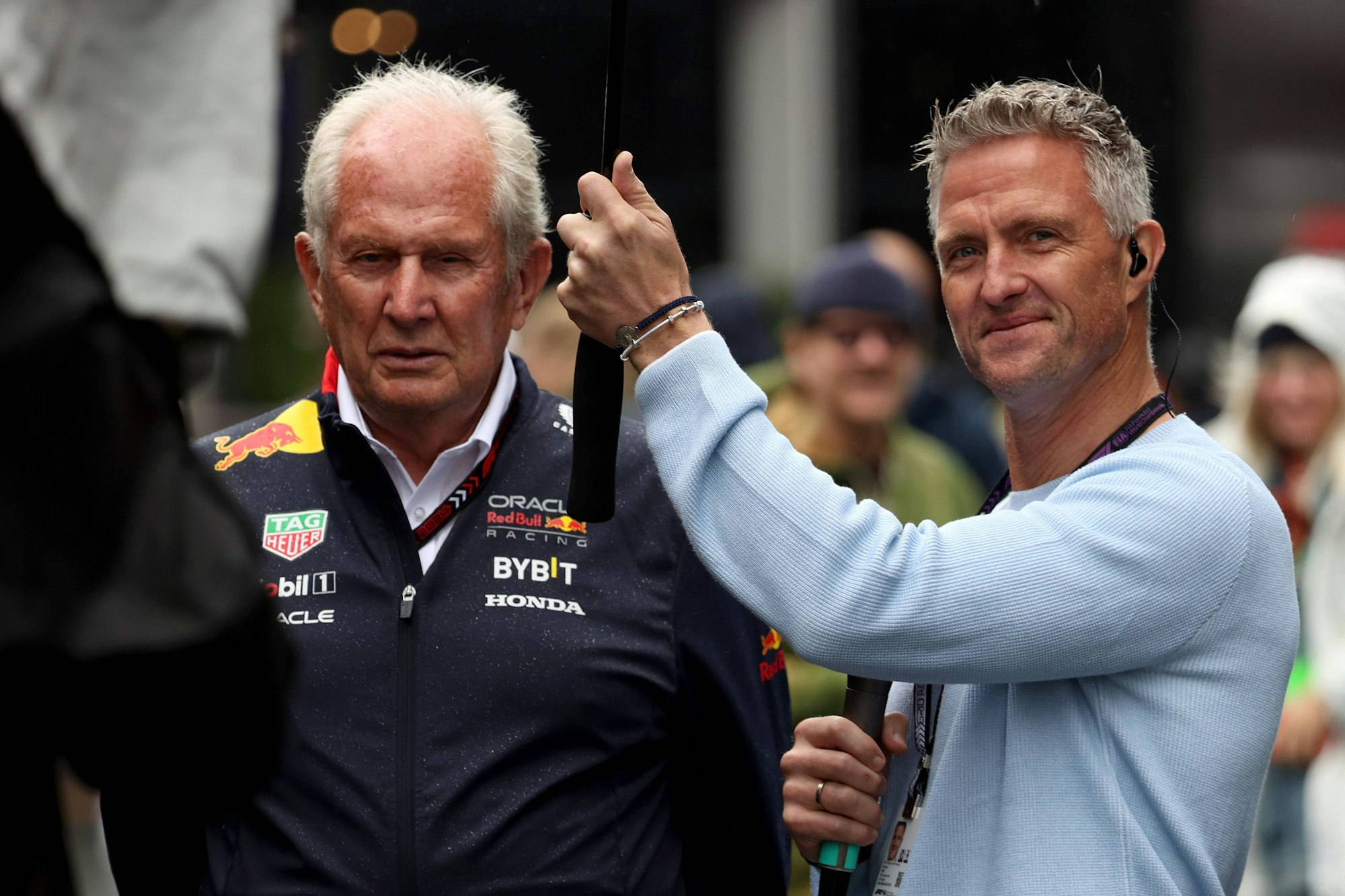 Ralf Schumacher hält bei einem Interview einen Schirm über Helmut Marko.