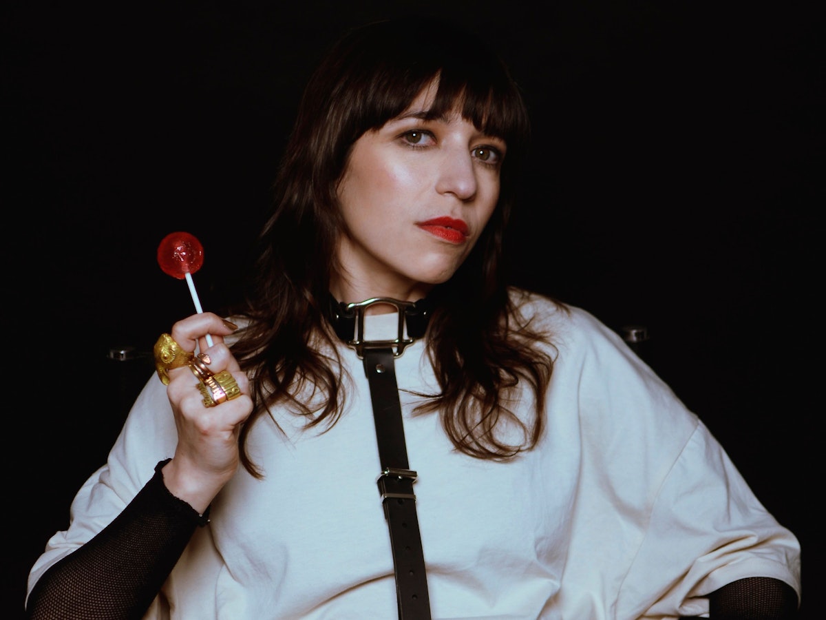 Paulita Pappel blickt in die Kamera und hält einen Lolli in der Hand.