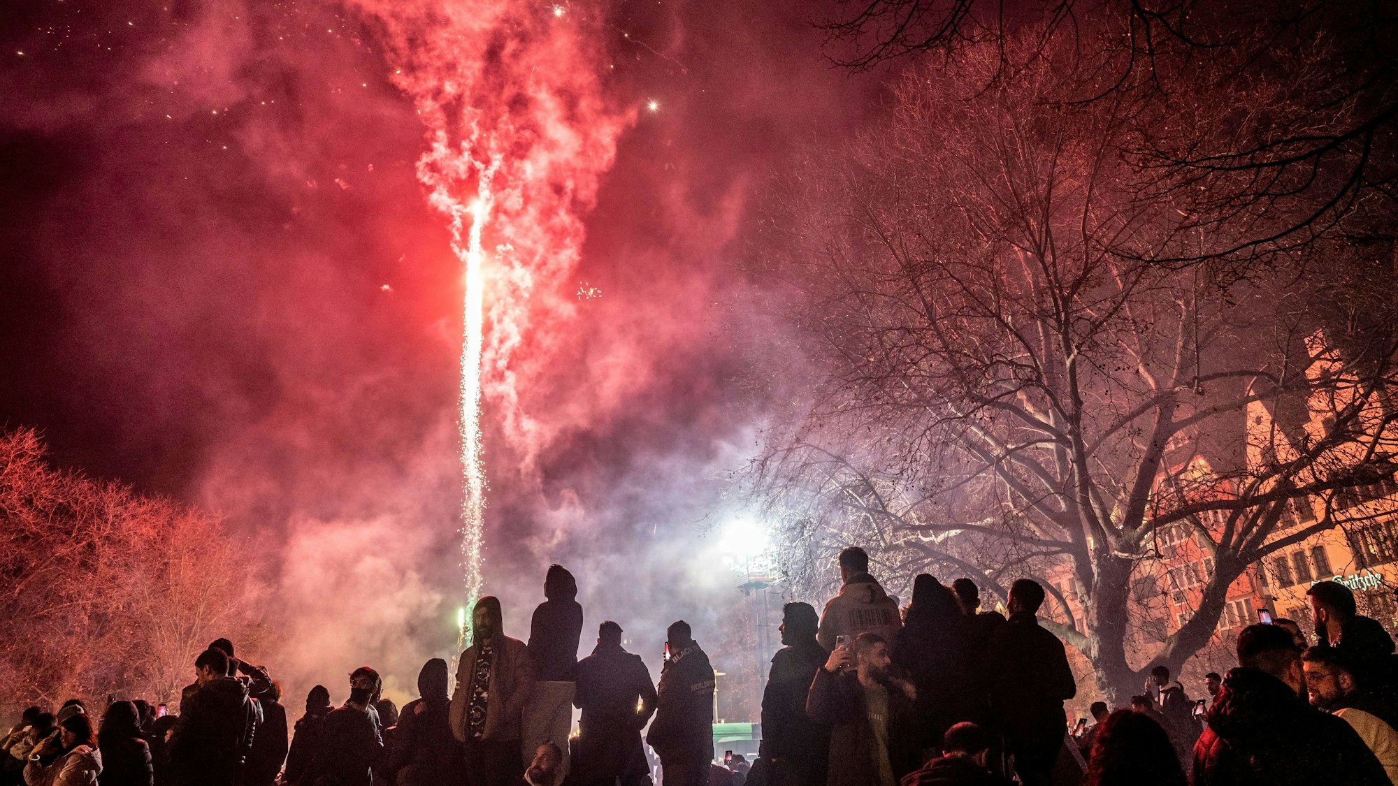 Feiernde lassen Silvesterraketen im Bereich der Kölner Altstadt in den Himmel steigen.