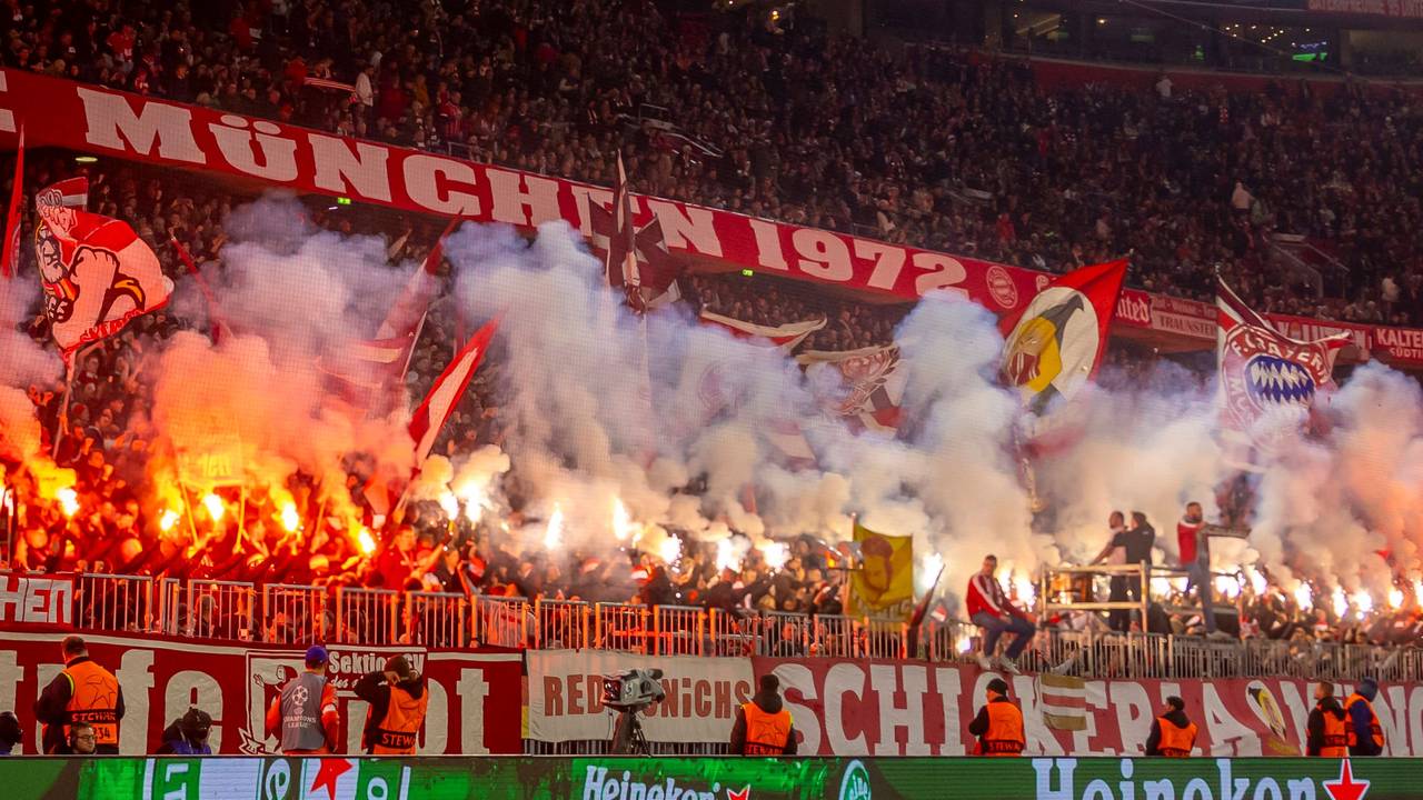 Die Fans des FC Bayern München zünden Pyro-Fackeln auf der Tribüne.