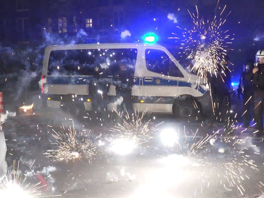 Polizeibeamte stehen am Silvesterabend 2022 hinter explodierendem Feuerwerk.
