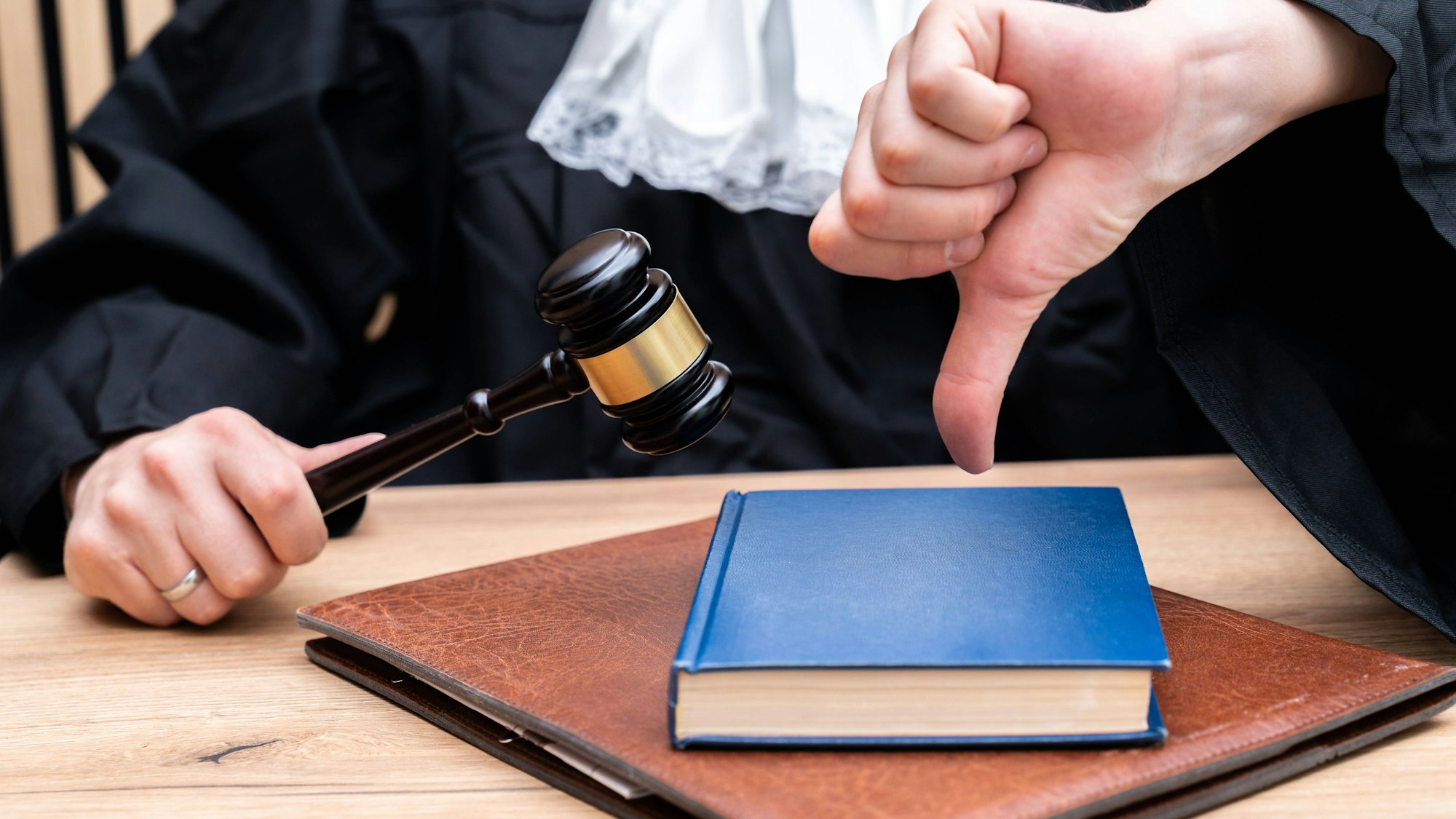 Richter mit Richterhammer zeigt Daumen nach unten