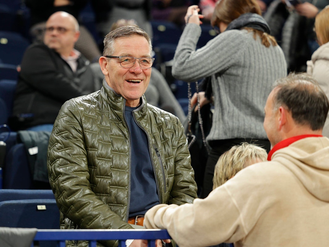 Alfred Gislason und Bob Hanning unterhalten sich lachend am Rande eines Spiels, wobei Hanning nur von hinten zu sehen ist.