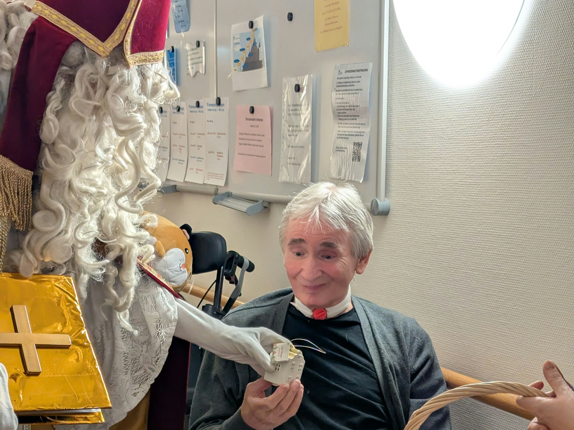 Ein alter Mann freut sich über ein Präsent, das ihm ein als Nikolaus verkleideter Mann überreicht.