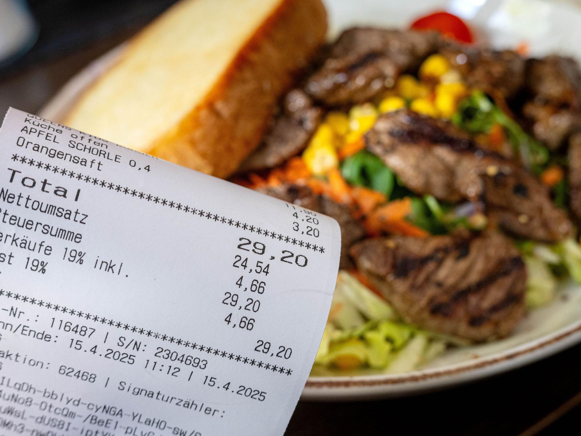 Eine Rechnung mit Mehrwertsteuer neben einem vollen Teller in einem Restaurant. Für die Gastronomie gibt es gute Nachrichten ausd em Bundesrat.