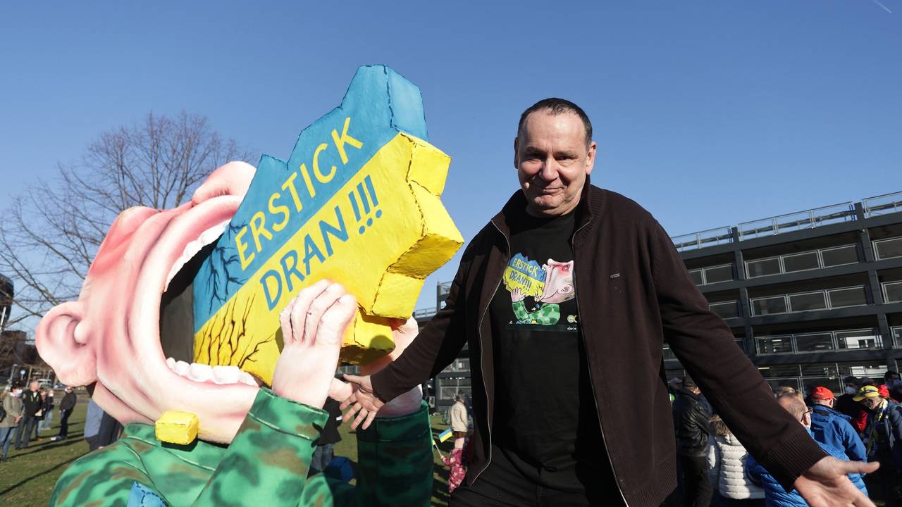 Jacques Tilly steht 2022 neben seiner kreierten Figur, die Putin zeigt, wie er an der Ukraine erstickt.