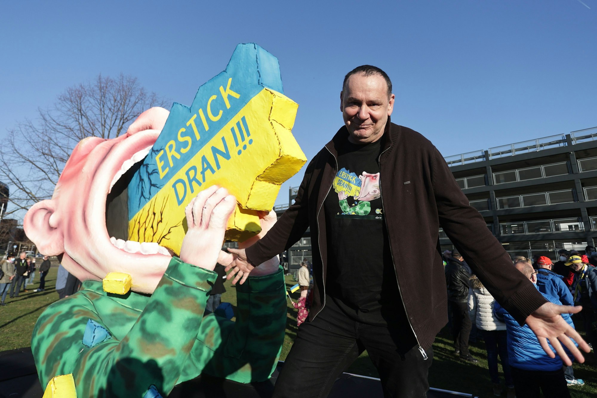 Jacques Tilly steht 2022 neben seiner kreierten Figur, die Putin zeigt, wie er an der Ukraine erstickt.