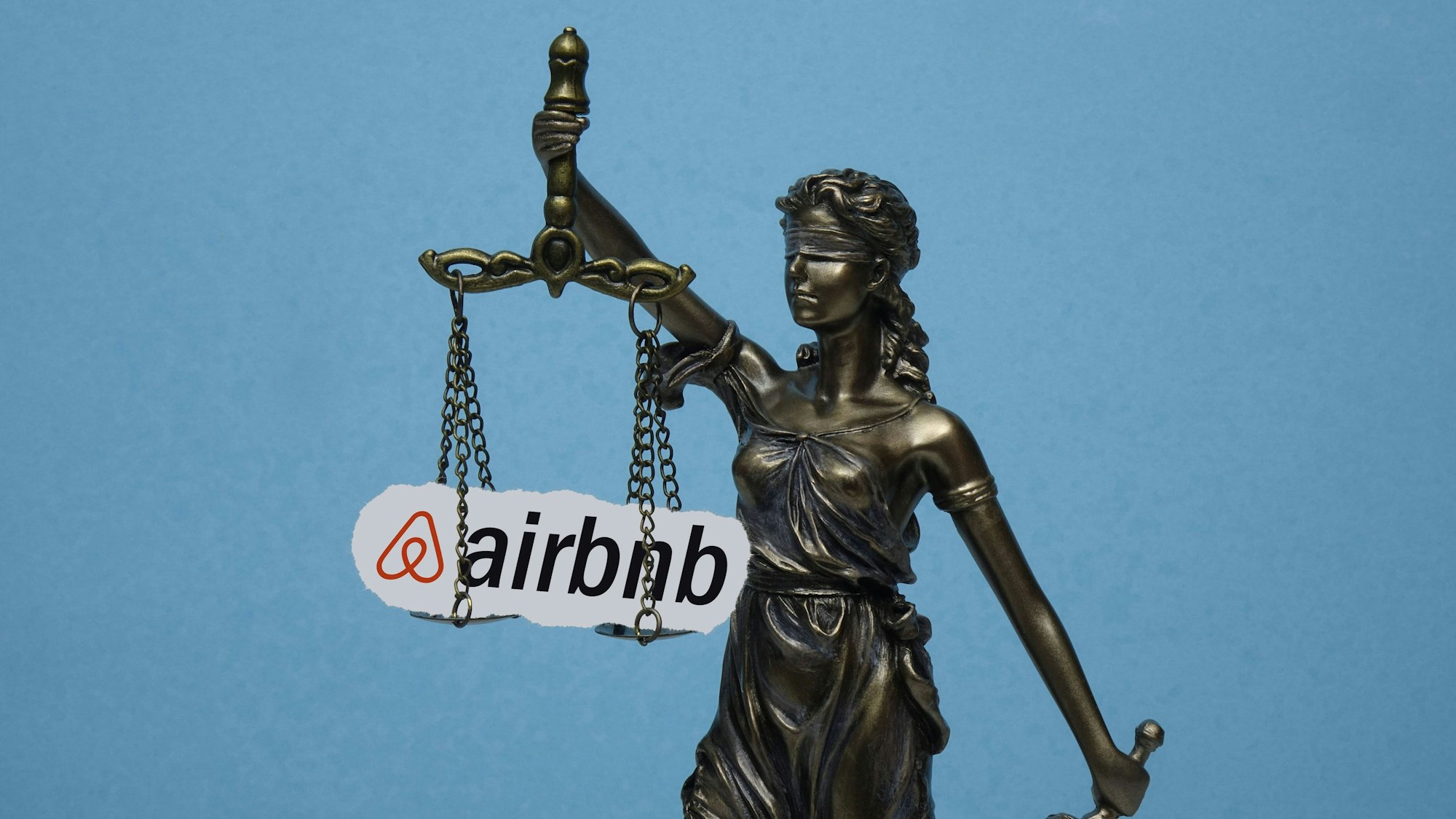 Statue der Justitia vor blauem Hintergrund mit Waage und Schriftzug