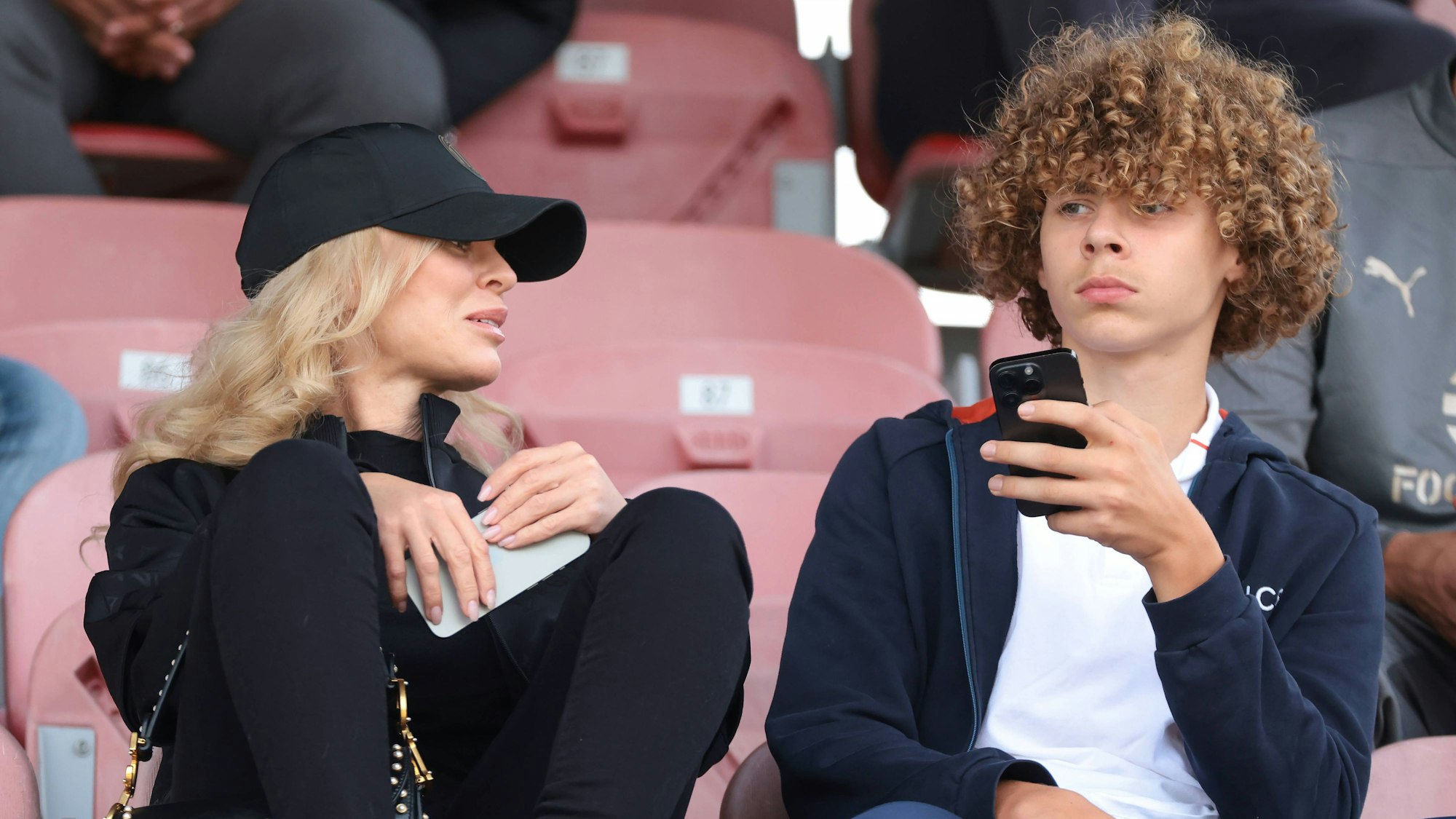 Vincent Ibrahimovic sitzt bei einem Spiel auf der Tribüne neben seiner Mutter.