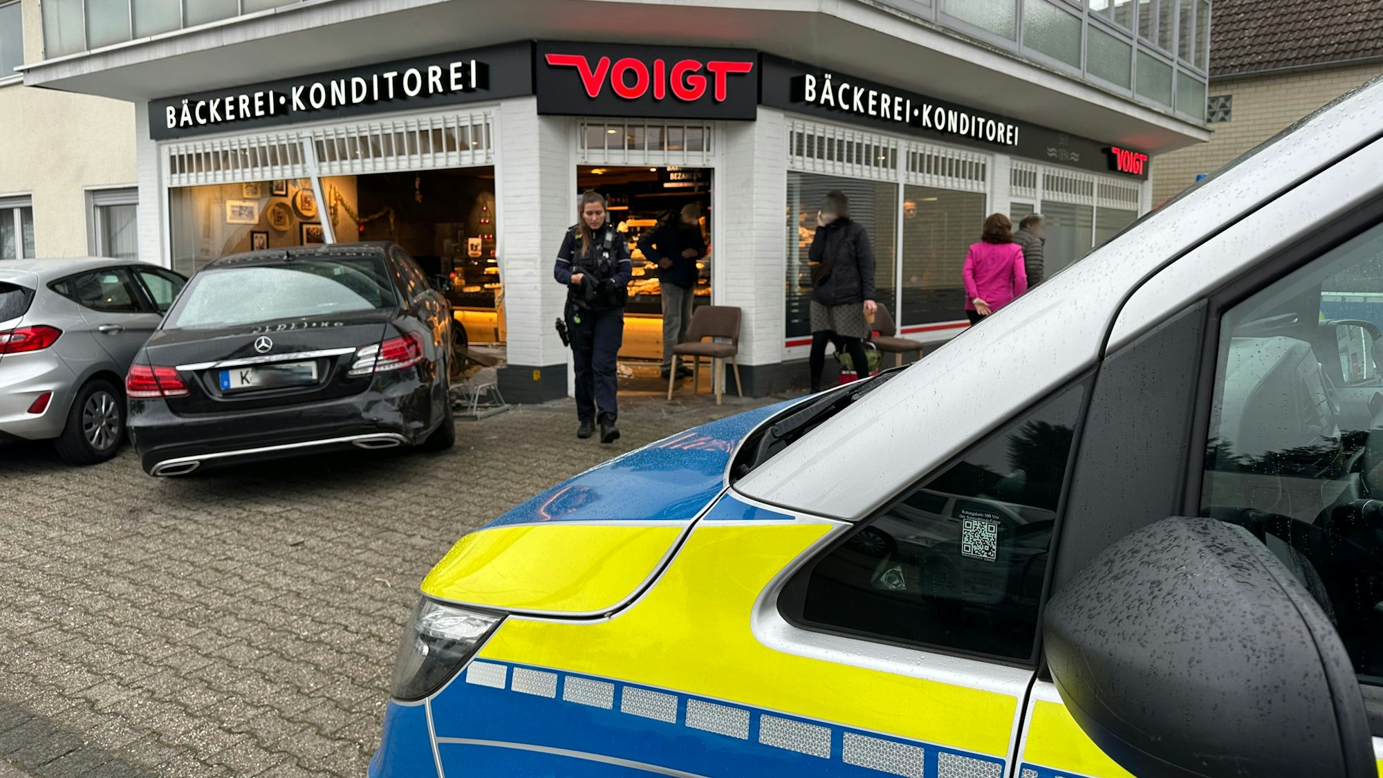 Polizei ist vor einer Bäckerei im Einsatz, in ein dortiges Schaufenster ist ein Auto gekracht.