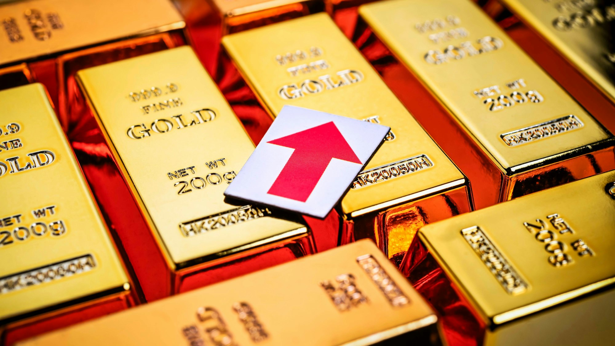 Goldbarren und roter steigender Pfeil