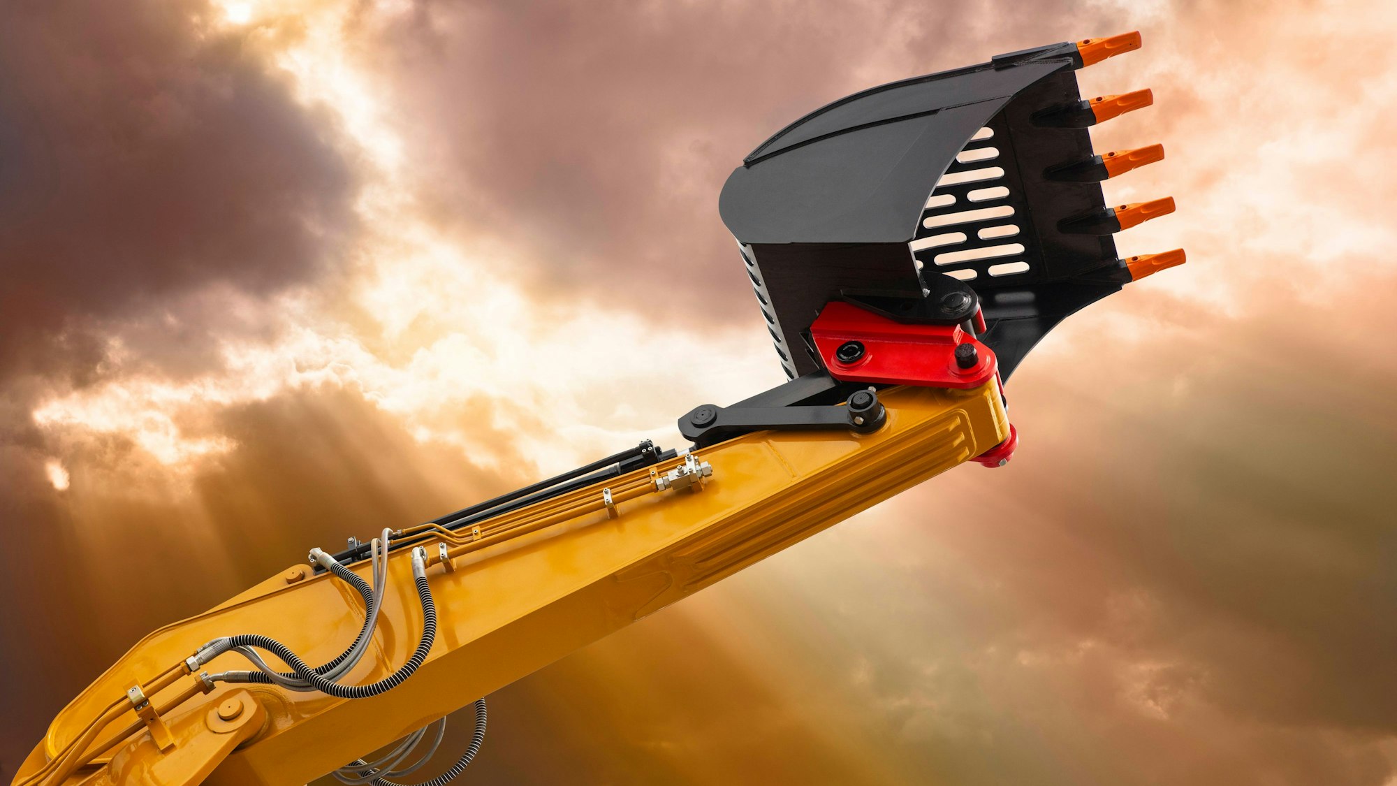 Gelber Baggerarm und Schaufel vor dramatischem Himmel mit Strahlen