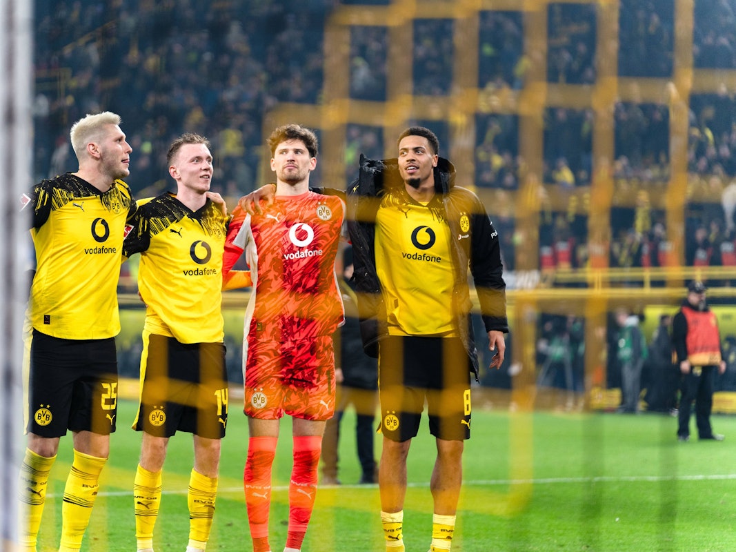 Niklas Süle (l.) feiert Arm in Arm mit seinen Teamkollegen auf dem Platz.