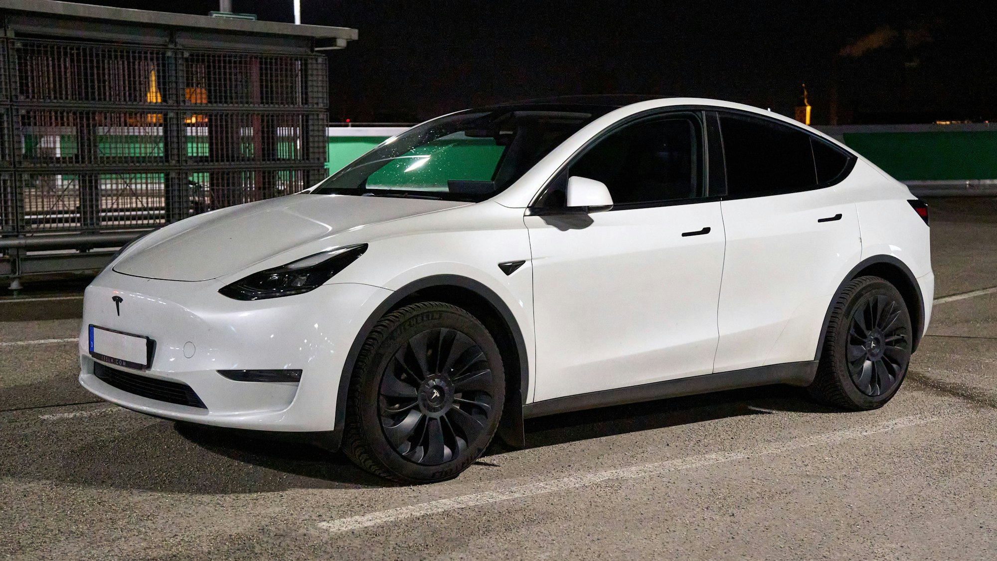 Ein weißes Elektroauto geparkt auf einem Parkplatz bei Nacht