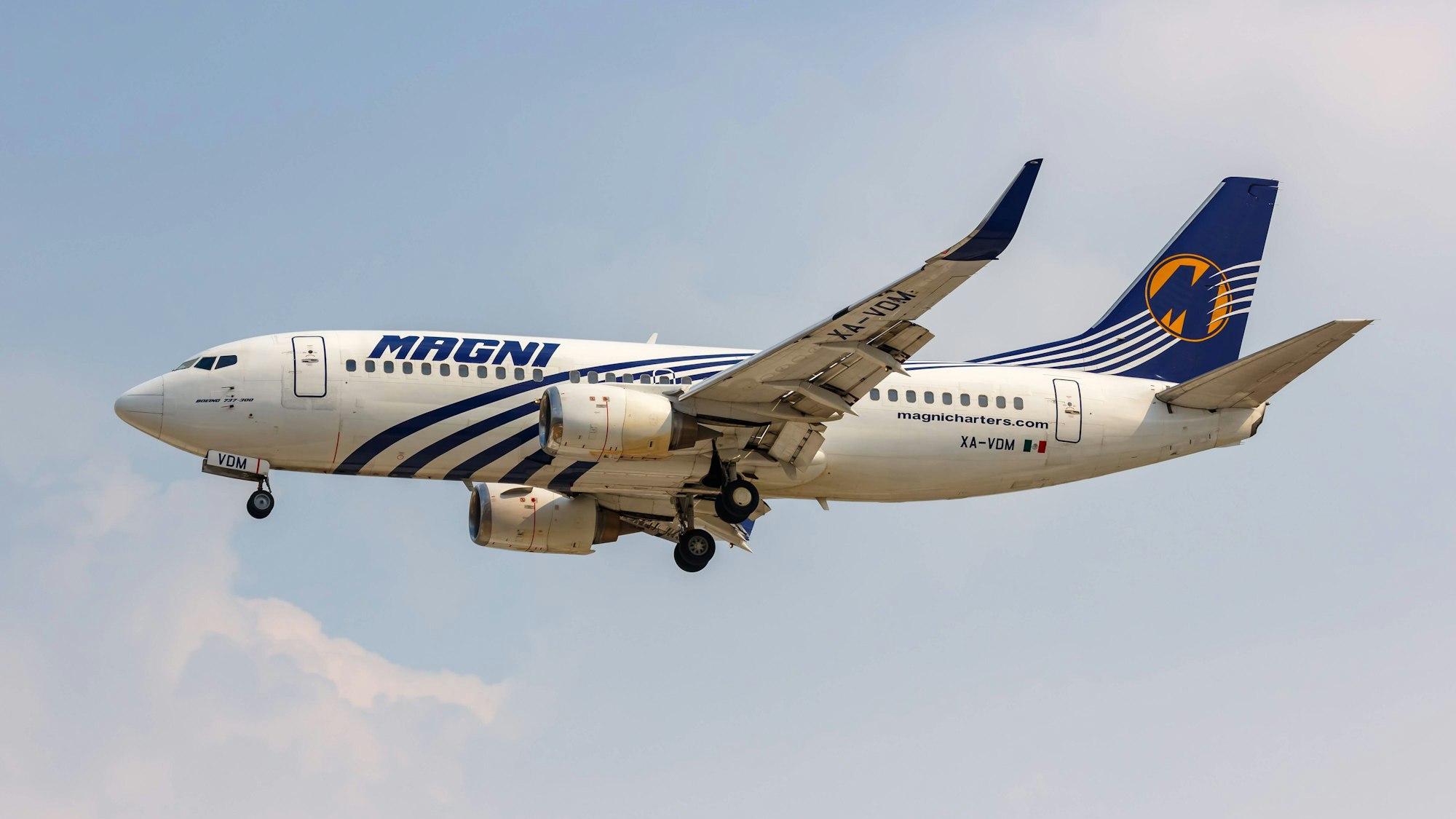 Flugzeug im Flug mit ausgefahrenem Fahrwerk vor blauem Himmel