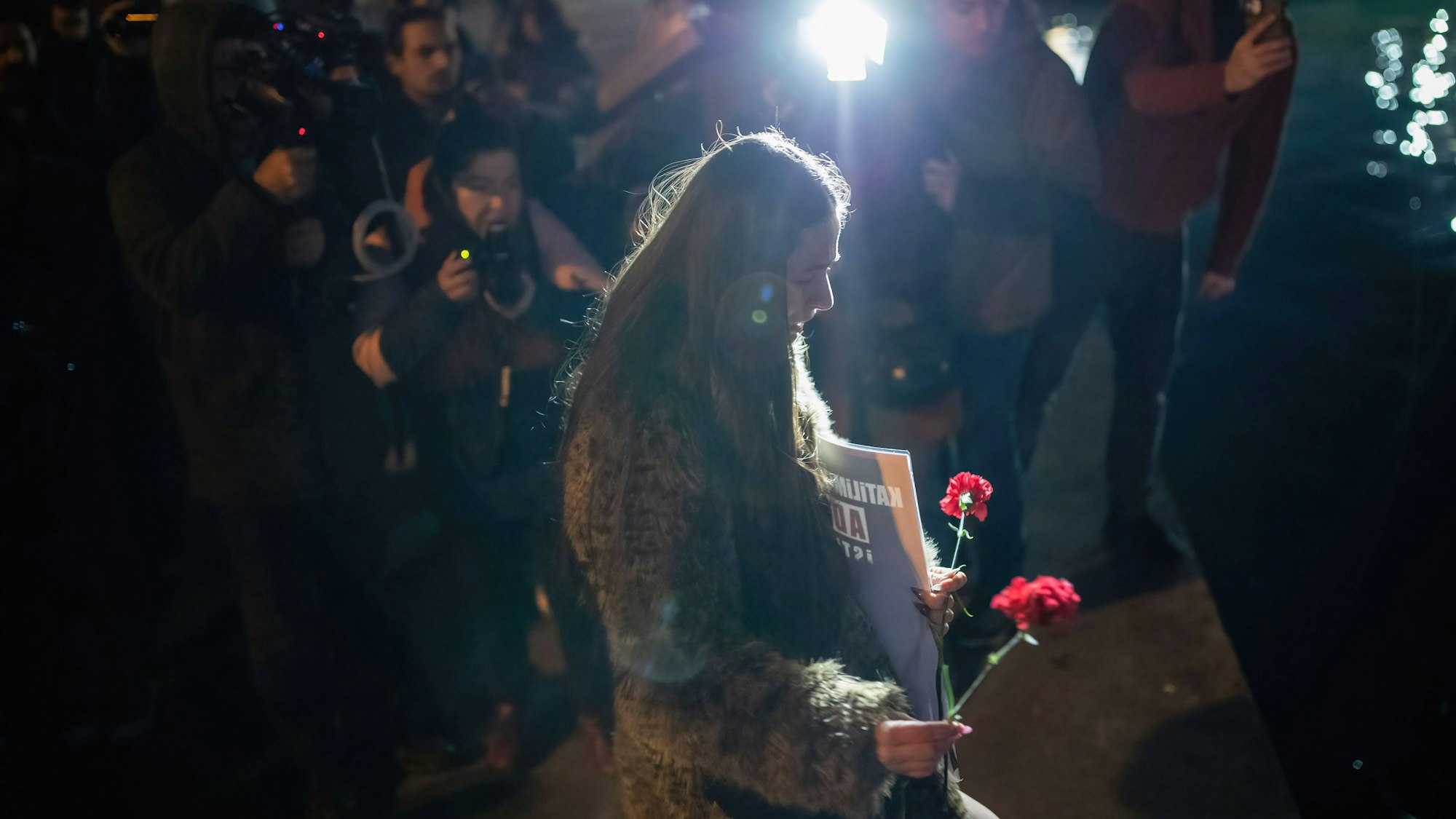 Frau mit Nelke und Schild bei Erdbeben-Gedenkfeier