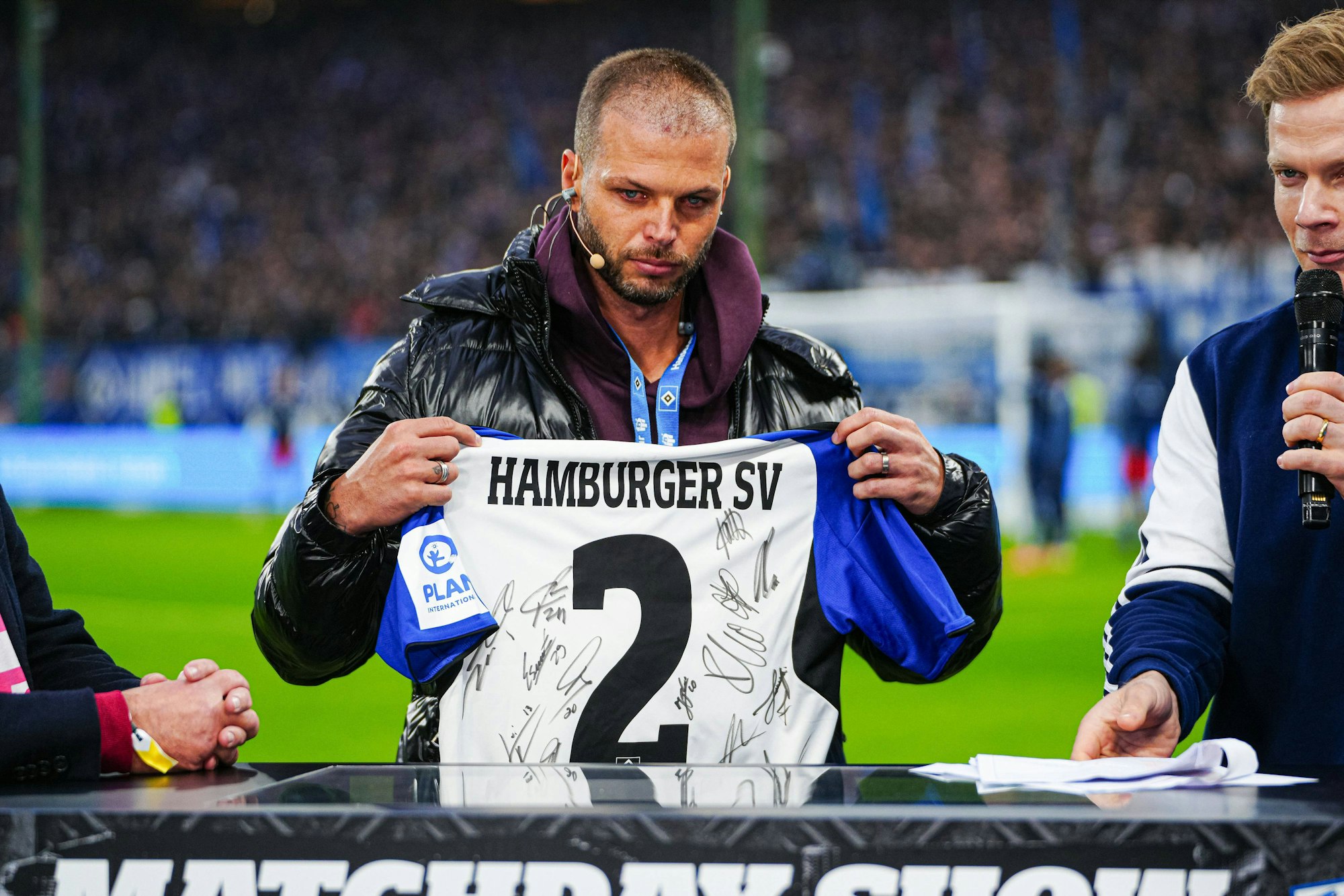 Dennis Diekmeier hält ein HSV-Trikot mit Autogrammen der Spieler für seine Tochter Delani in die Kamera.