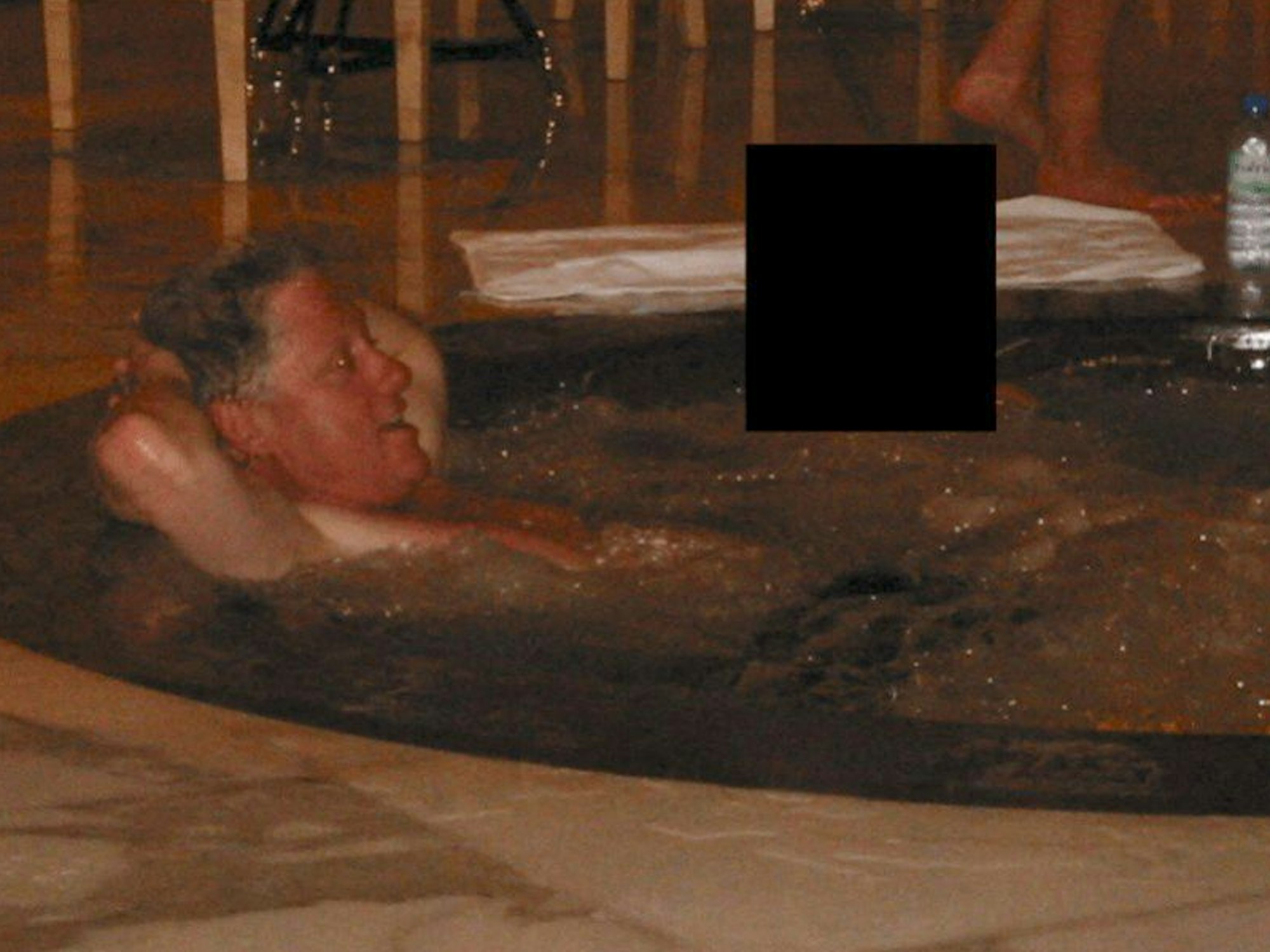 Ein Mann liegt in einem Whirlpool, neben ihm eine Person, die unkenntlich gemacht wurde.