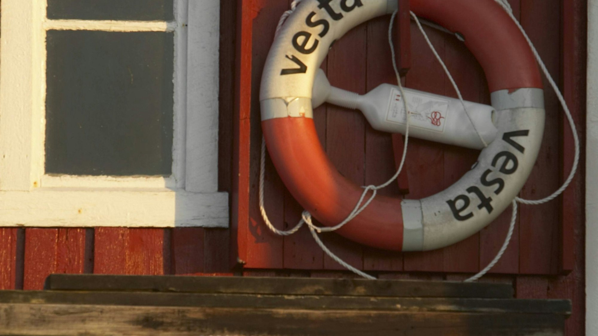 Rotes Holzhaus mit Fenster, Rettungsring und gestapelten Behältern