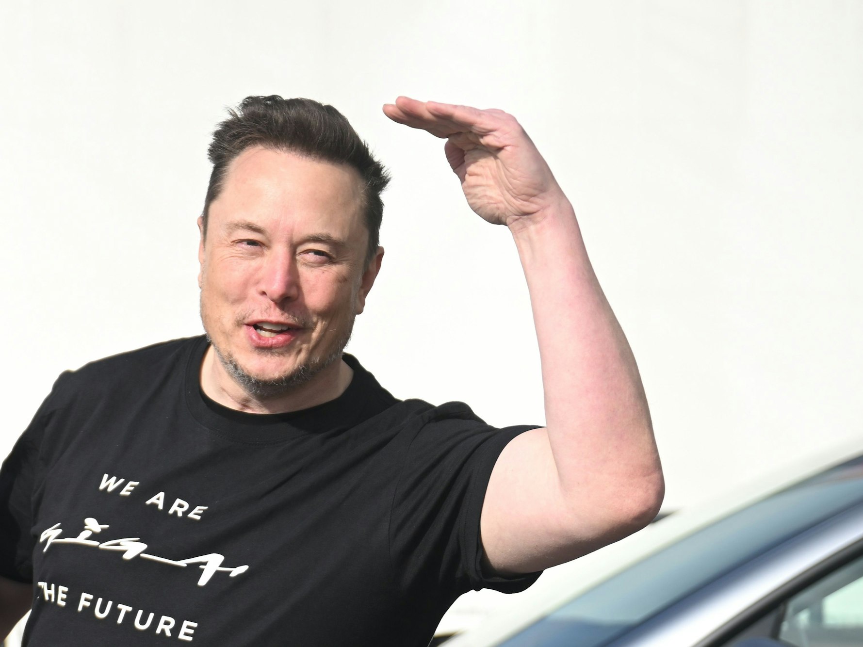 Elon Musk grüßt mit erhobener Hand.
