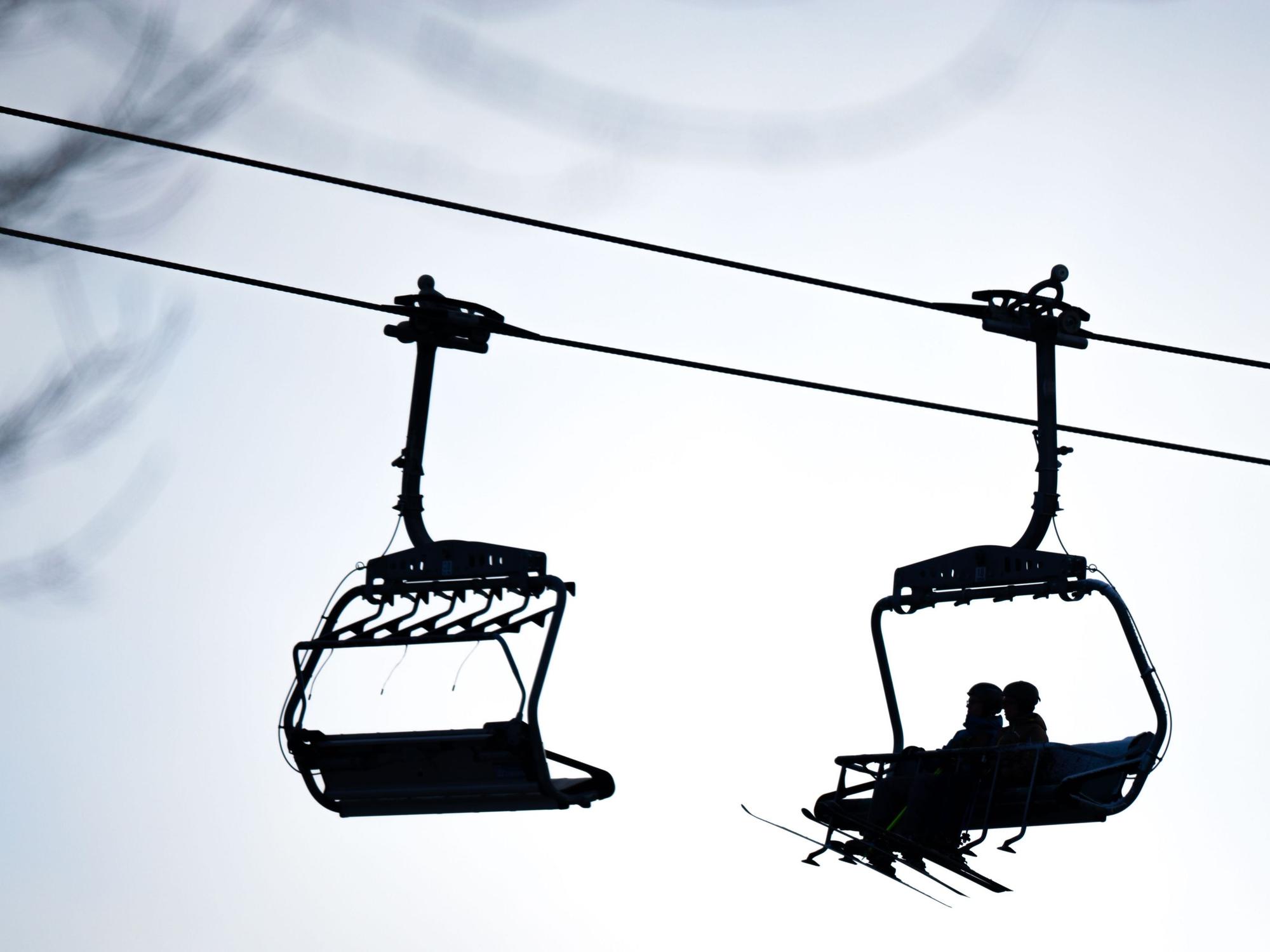 Skifahrer sitzen in einem Sessellift.
