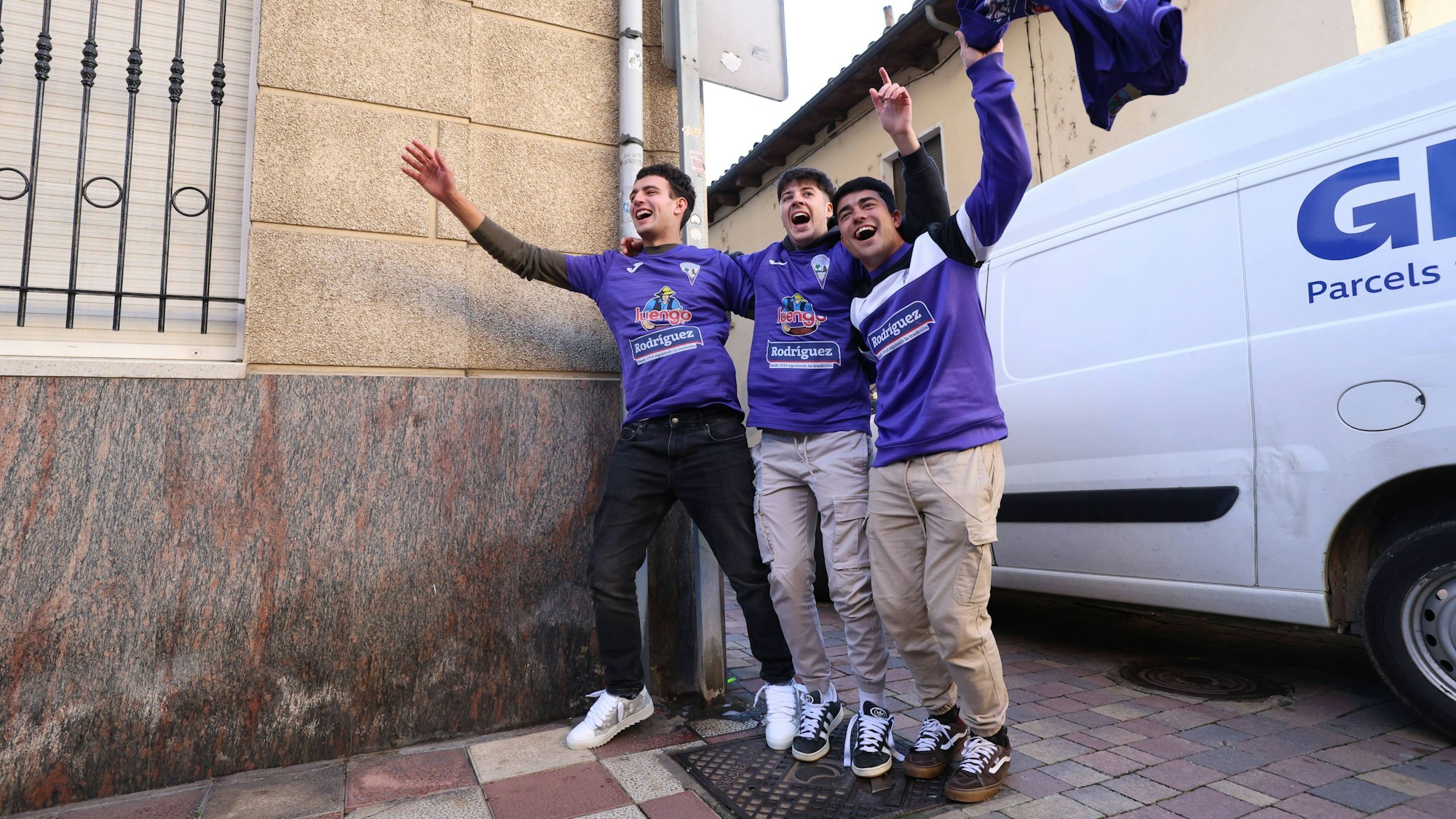 Lotto-Gewinner im Trikot des La Bañeza Fútbol Club jubeln auf der Straße.