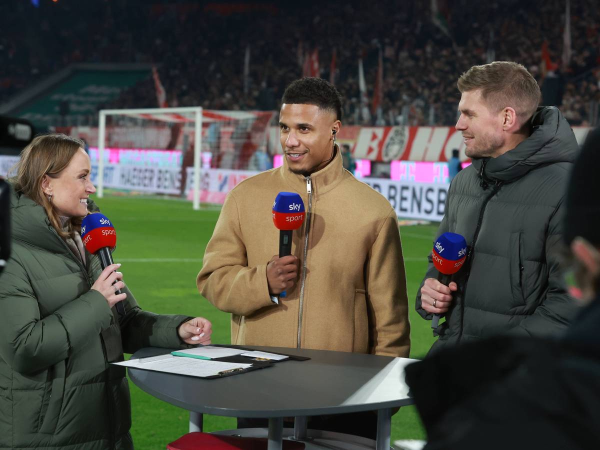 Ismail Jakobs steht bei Sky am Tisch und spricht in ein Mikrofon.