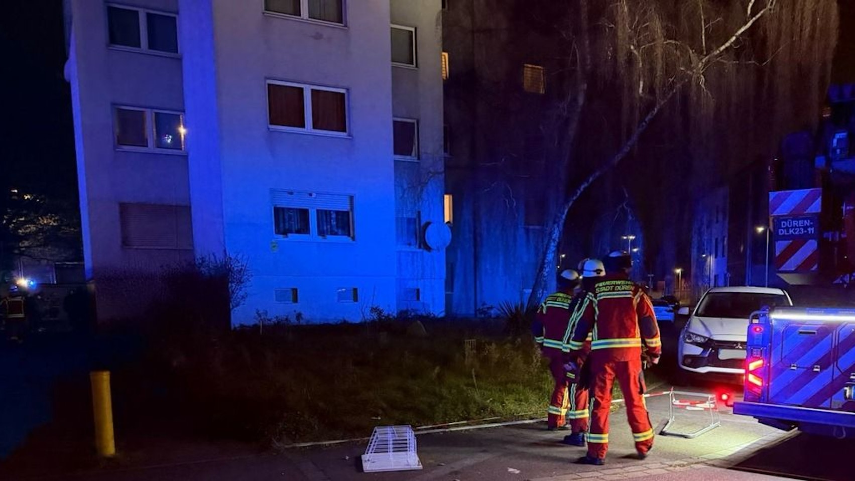 Ein Feuerwehrmann in Schutzkleidung mit Atemschutzmaske steht vor einer Wohnungstür.