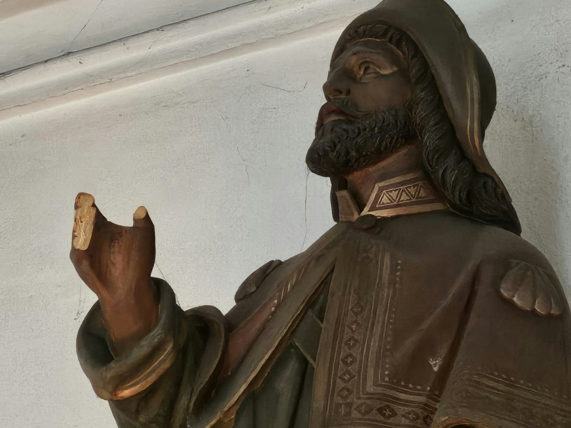 Eine Figur hält eine Hand hoch, an der alle Finger abgebrochen sind.