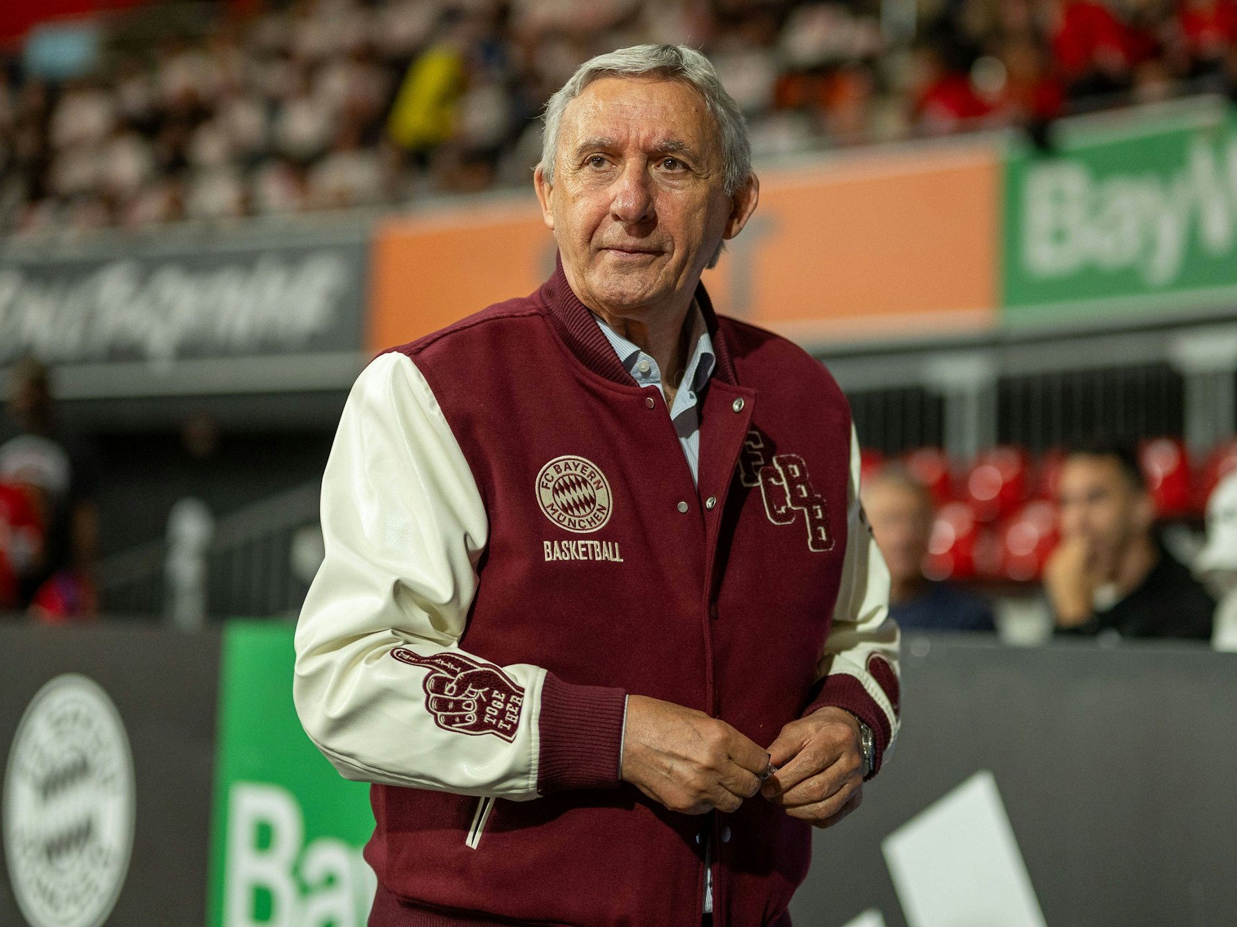 Svetislav Pesic trägt eine College-Jacke des 1. FC Köln.