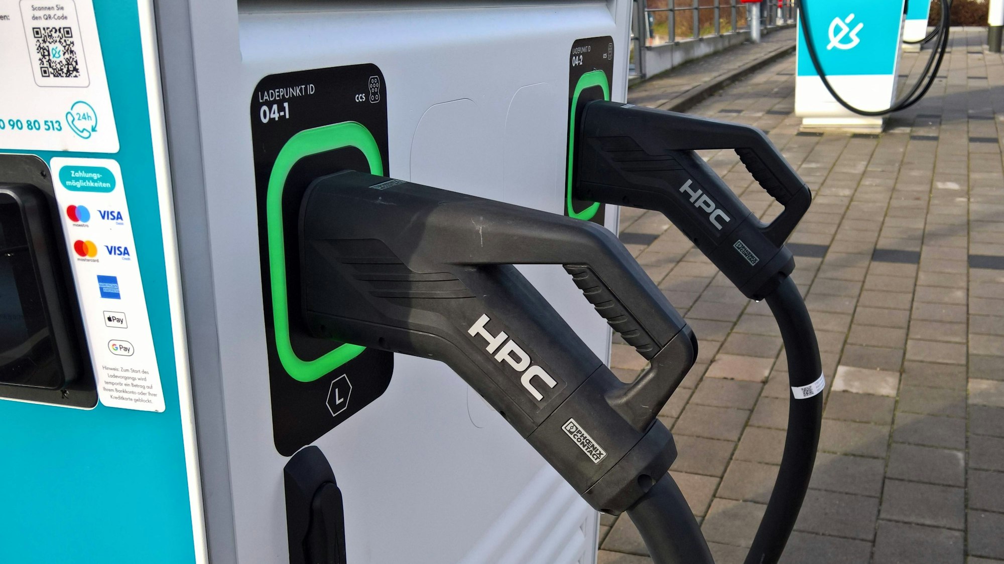 Zwei Ladesäulen für Elektrofahrzeuge mit angeschlossenen Kabeln