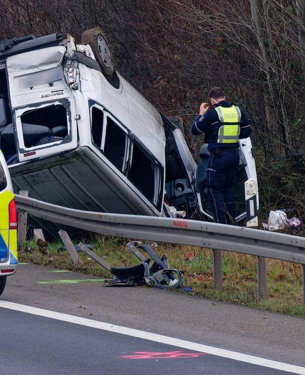Ein Transporter liegt neben der Autobahn auf dem Dach.