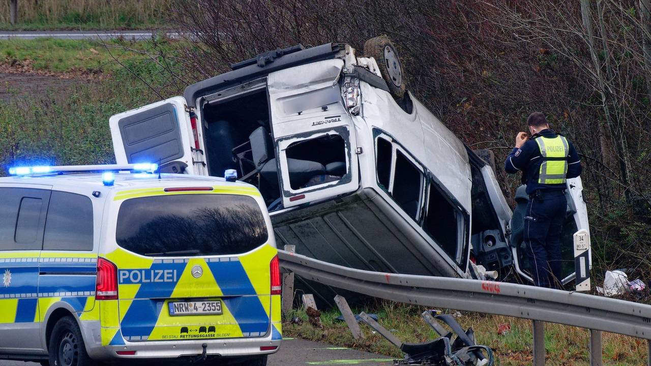 Ein Transporter liegt neben der Autobahn auf dem Dach.
