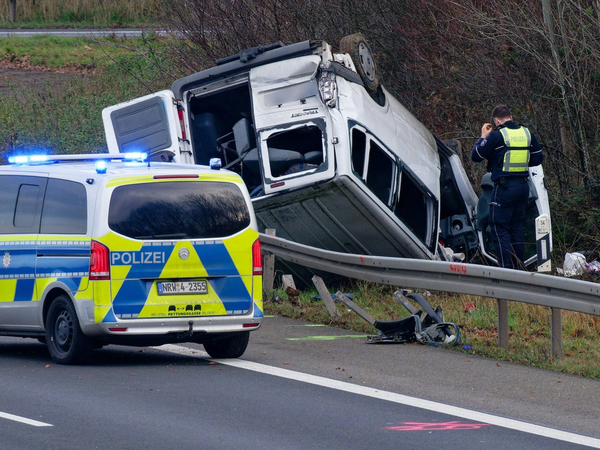 Ein Transporter liegt neben der Autobahn auf dem Dach.