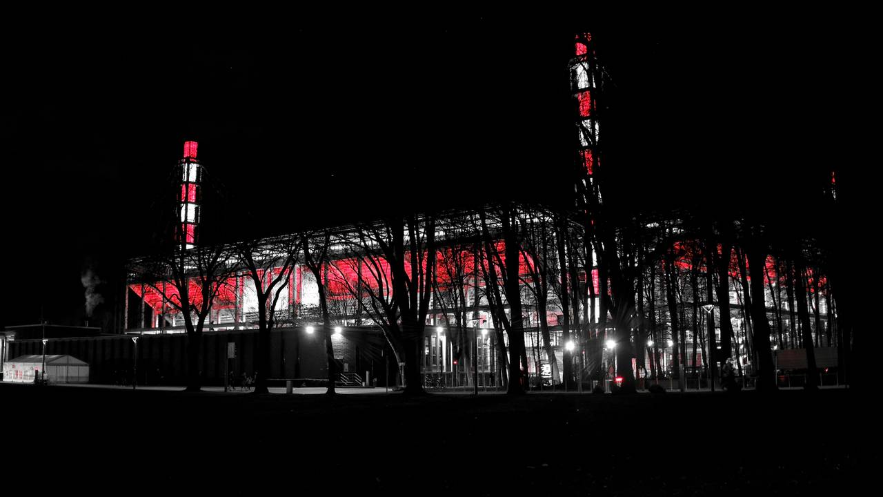 Das Stadion des 1. FC Köln leuchtet bei Nacht in rot und weiß.