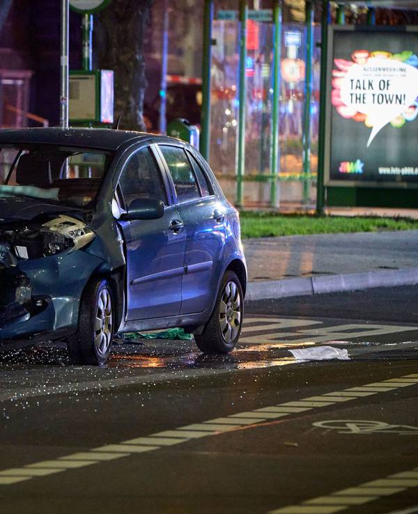 Ein beteiligtes Fahrzeug steht an der Unfallstelle, in der Nähe einer Bushaltestelle. Ein Mann verletzt mit einem Auto in Gießen mehrere Menschen.