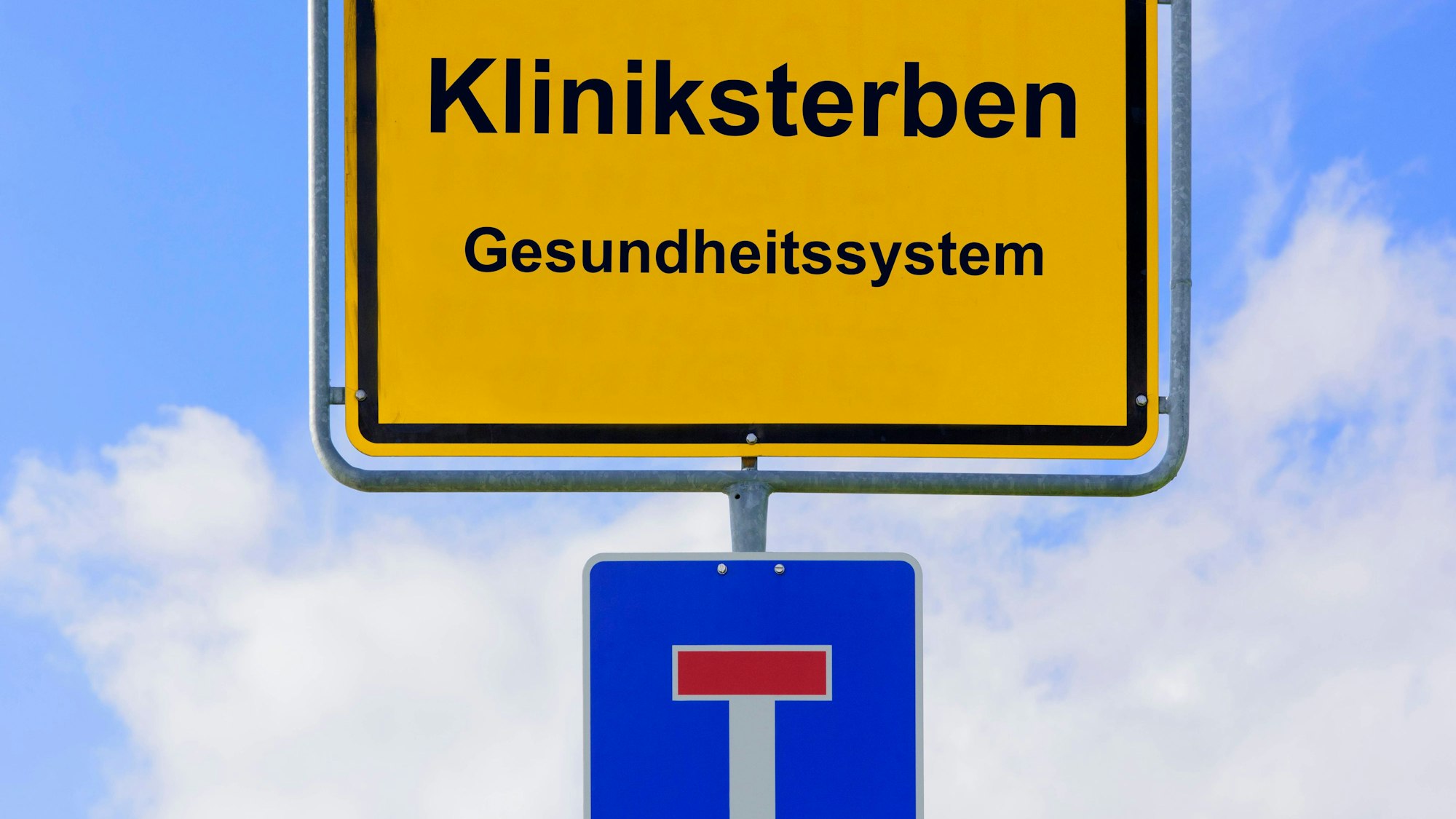 Schilder mit „Kliniksterben“, „Gesundheitssystem“ und Sackgassensymbol