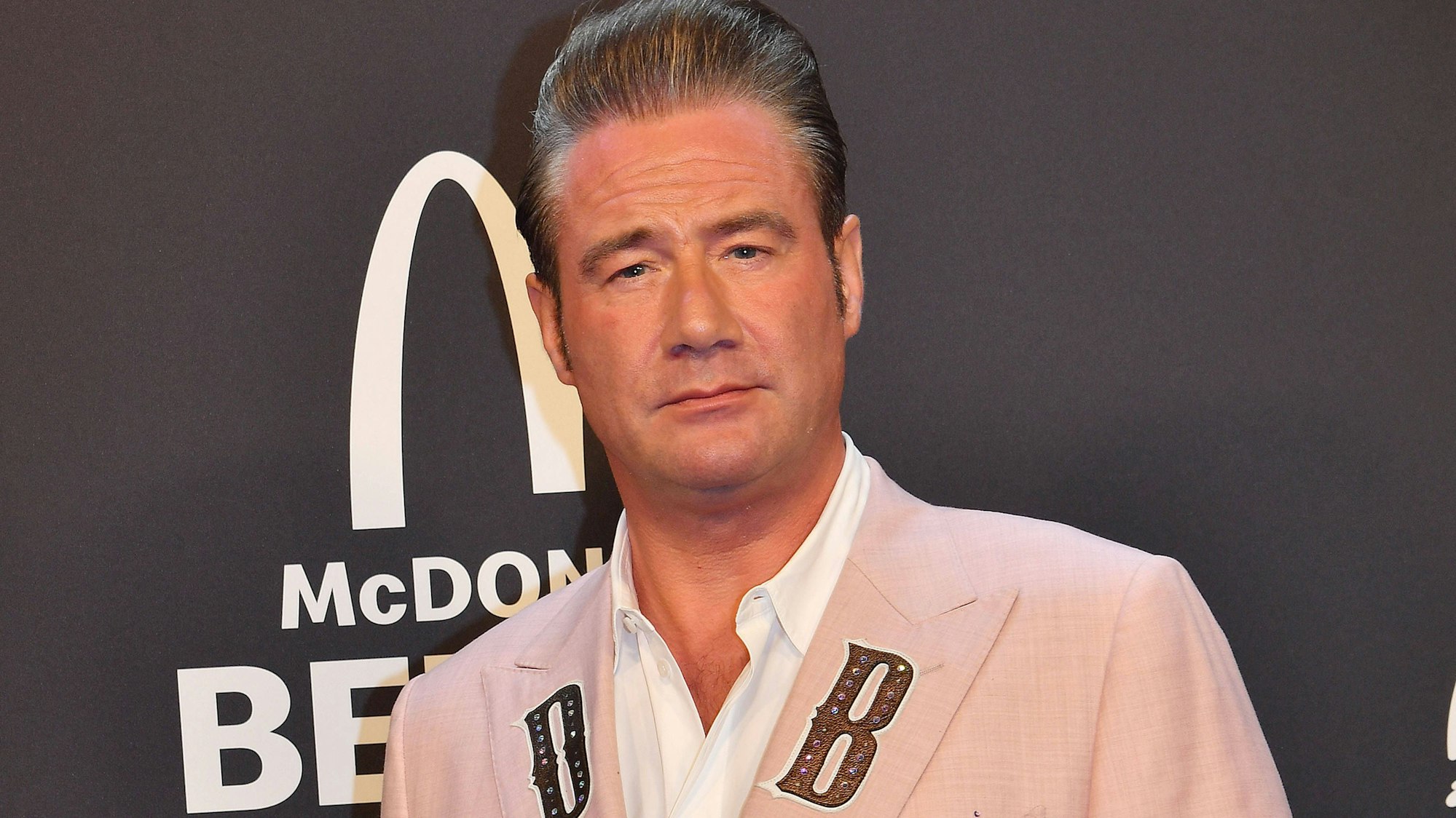 Sasha (Dick Brave) in hellem Anzug bei Gala