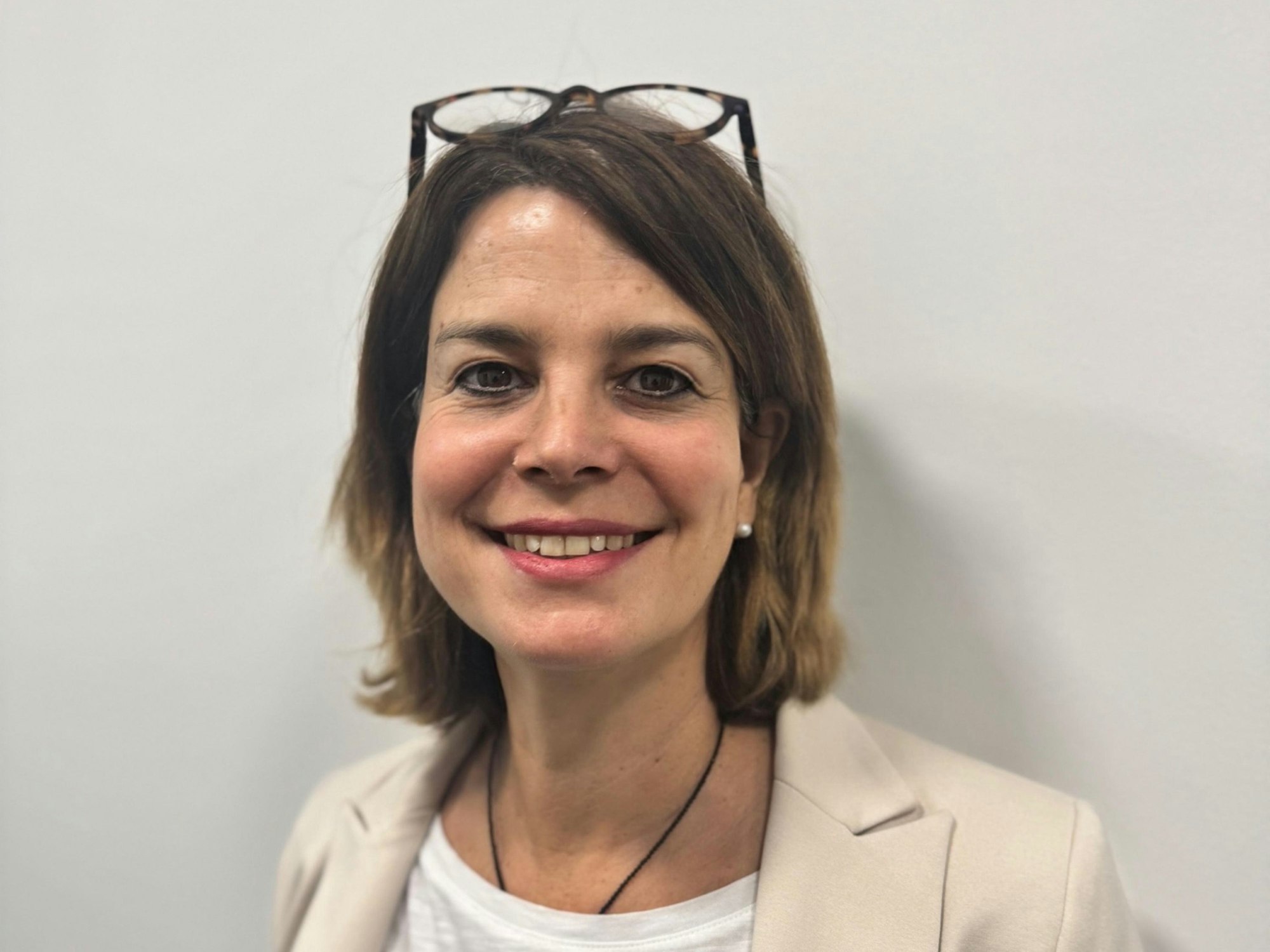Eine Frau mit halblangen braunen Haaren hat eine Brille auf den Kopf geschoben und schaut freundlich in die Kamera.