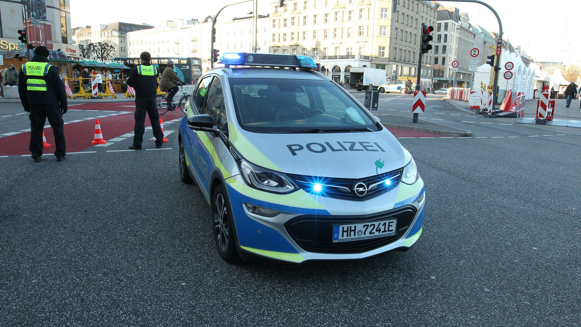 Polizeiauto mit Blaulicht und Polizisten