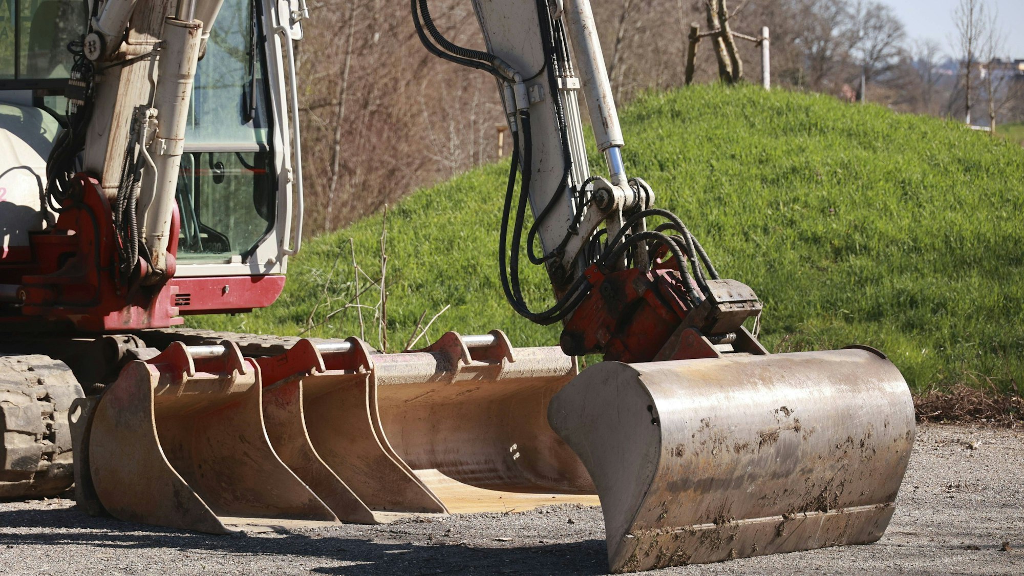 Baufahrzeug mit verschiedenen Schaufeln auf Schotter
