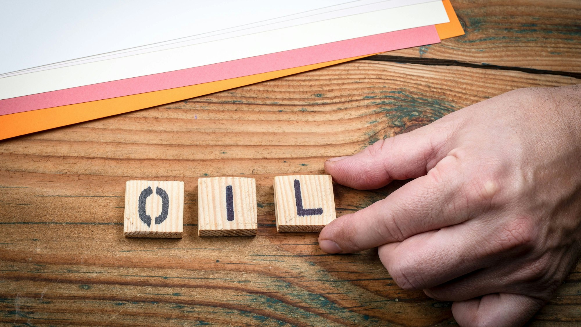Hand auf Holzbrett mit Buchstaben und Papier