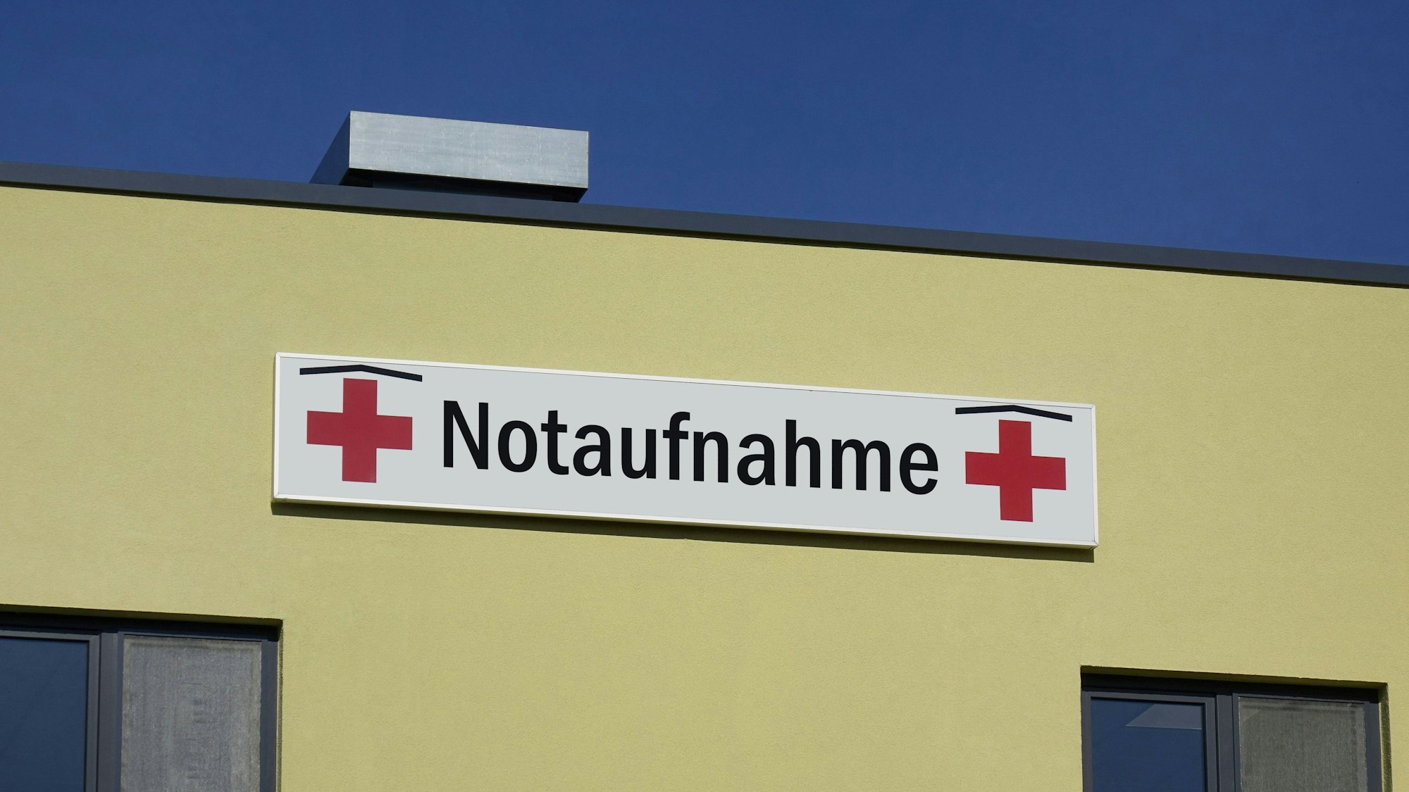 Krankenhaus-Gebäude mit Notaufnahme-Schild unter blauem Himmel