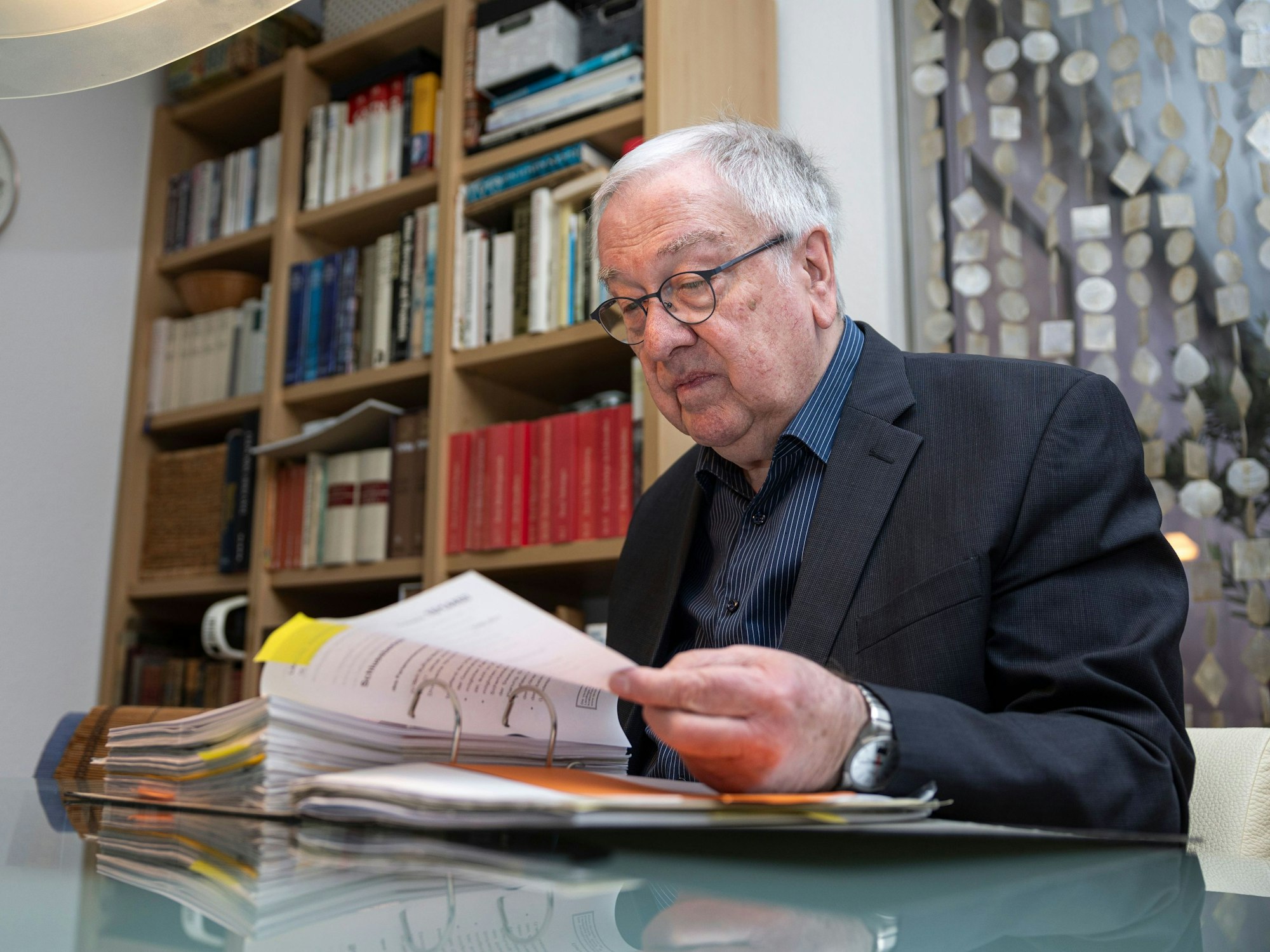 Der Rechtspsychologe Rudolf Egg sitzt an einem Tisch und blättert durch einen Ordner.