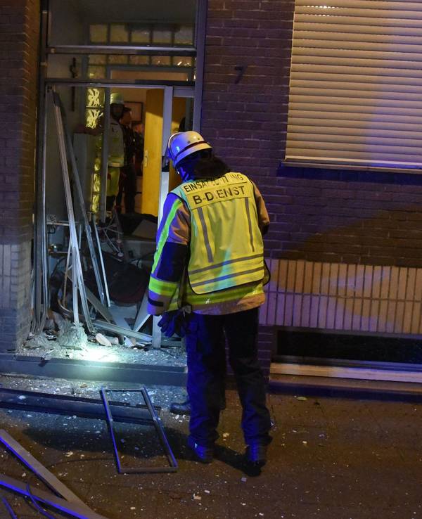 Ein Feuerwehrmann steht an der zerstörten Eingangstür.