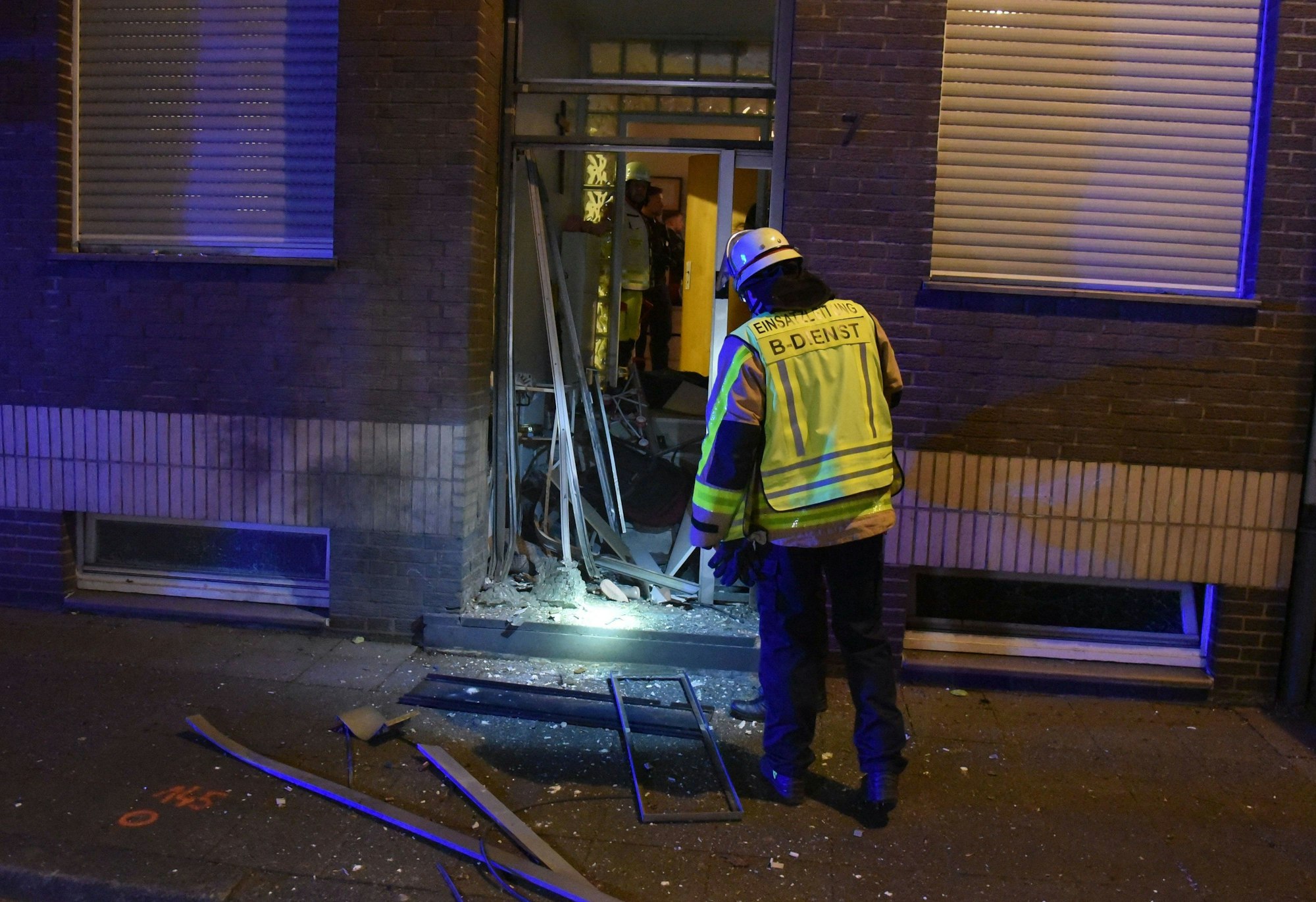 Ein Feuerwehrmann steht an der zerstörten Eingangstür.