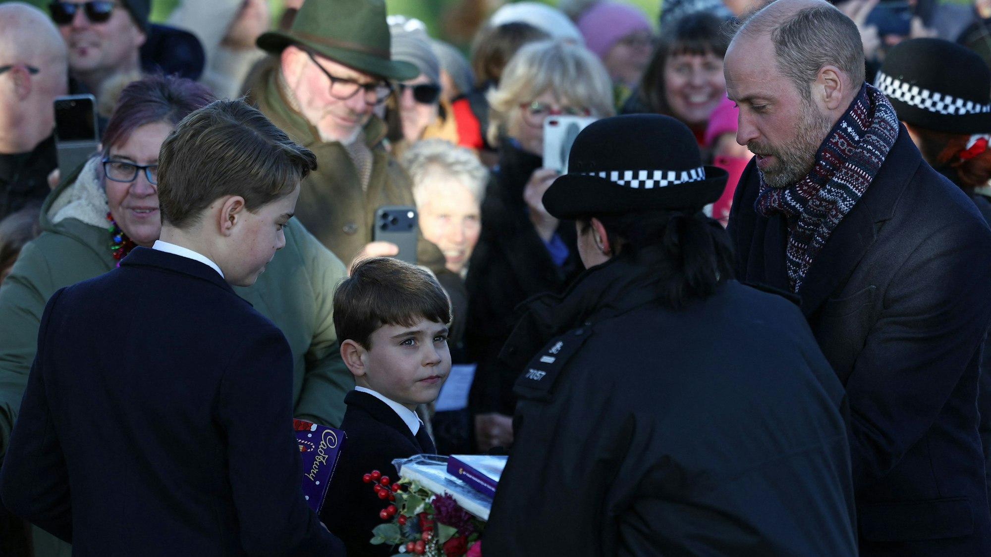 Eine Polizistin nimmt Geschenke entgegen, die von Gratulanten an den britischen Prinzen George von Wales (links), den britischen Prinzen Louis von Wales (Mitte) und den britischen Prinzen William, Prinz von Wales, überreicht wurden.