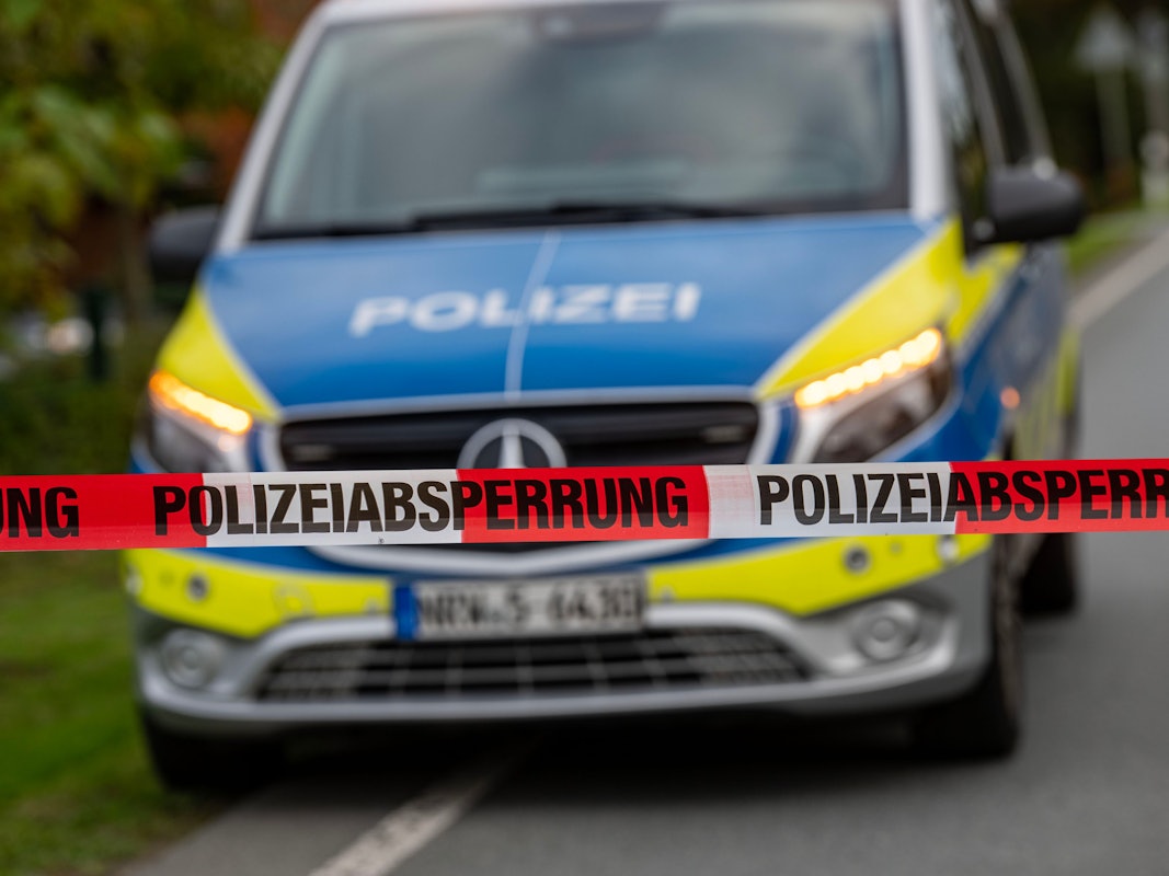 Polizeiauto hinter Polizeiabsperrband auf der Straße